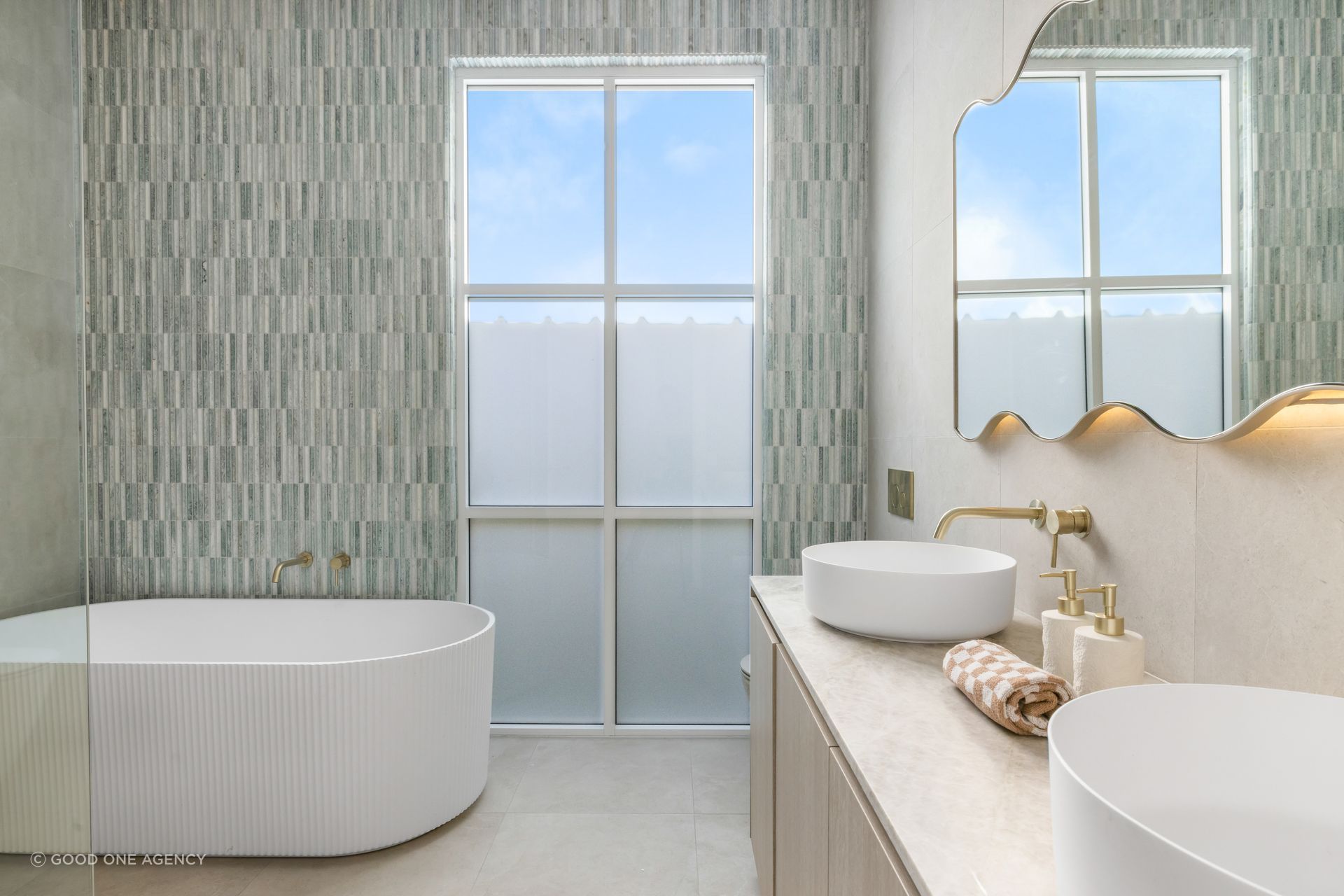 The main bathroom features a fluted porcelain tub and a pop of subtle colour in the green Moroccan tile feature wall.