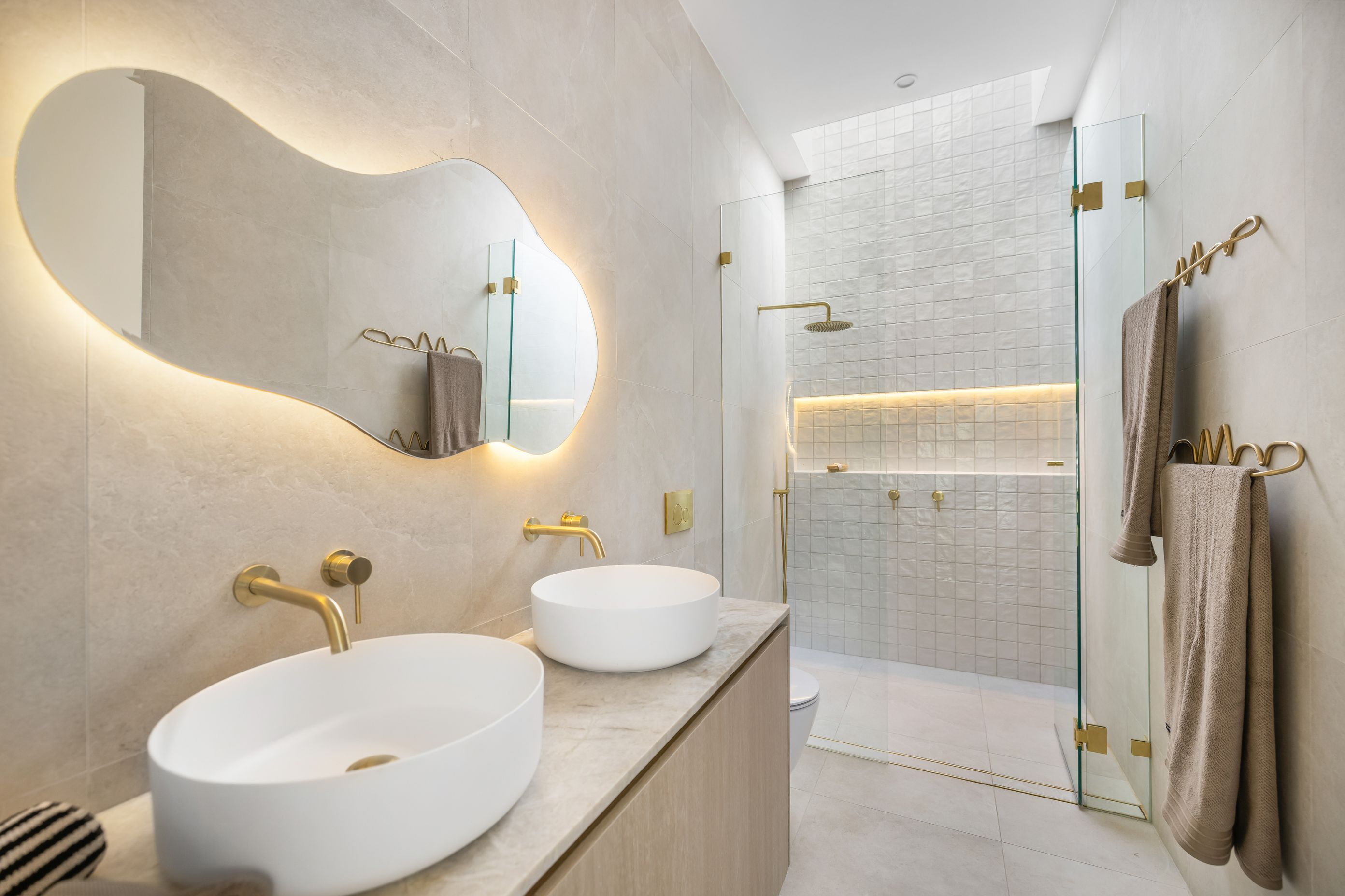 The master ensuite features brass accents against subtle tiling.