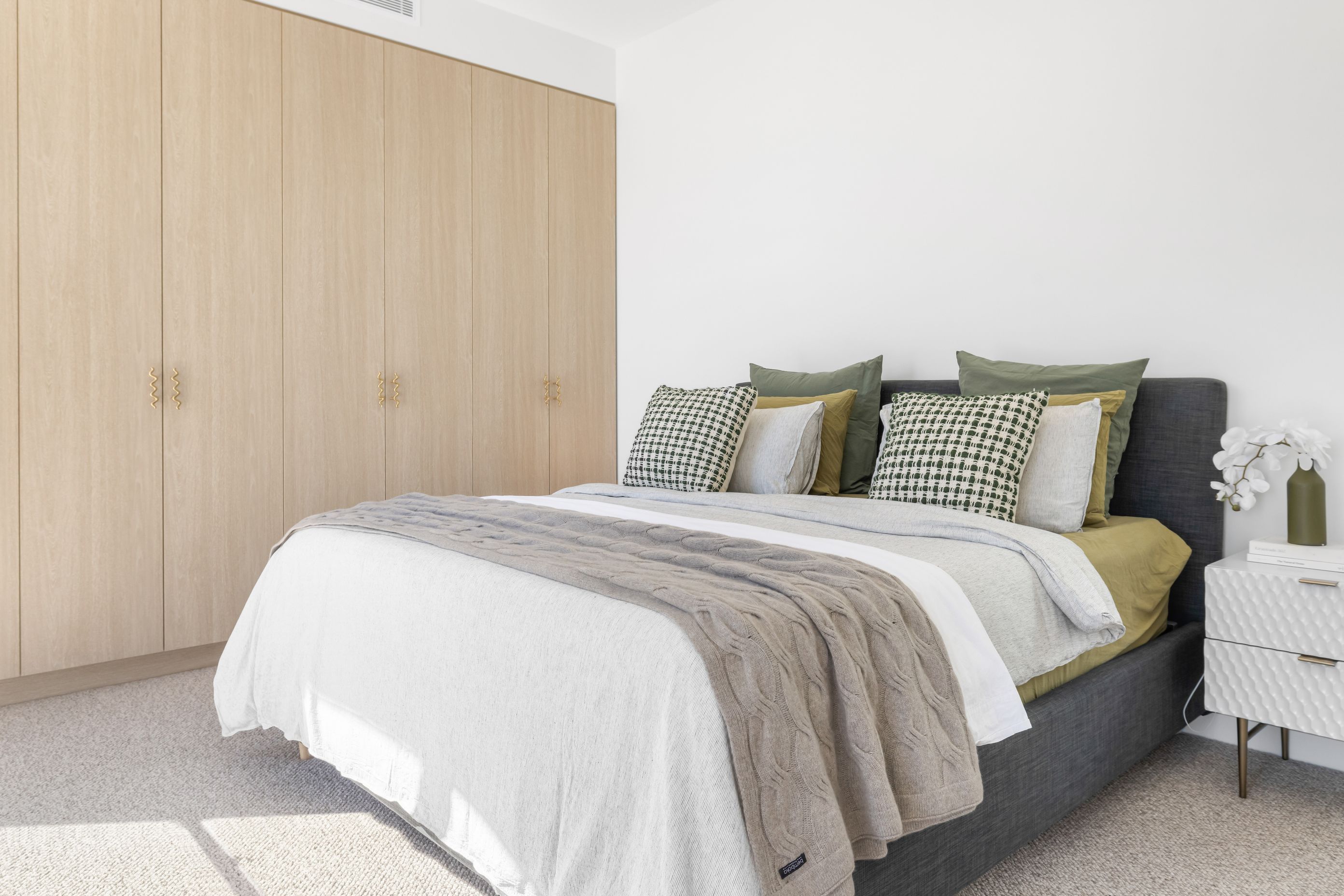The master bedroom features a soft material palette and the playful squiggle handles that are found throughout the home.