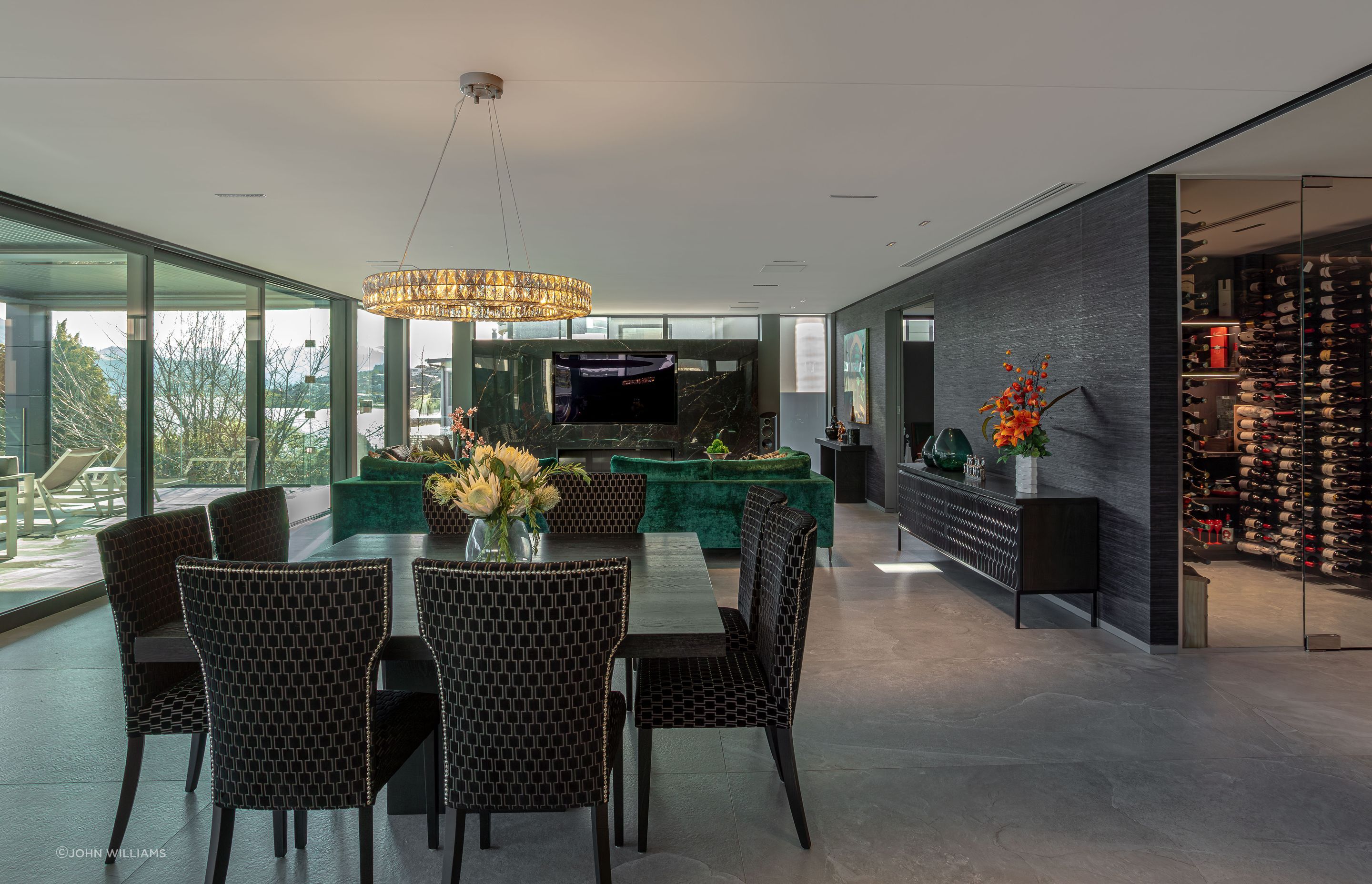 Descending from the foyer, the home expands into a dramatic, open living, kitchen, and dining space complete with a pantry and wine cellar.