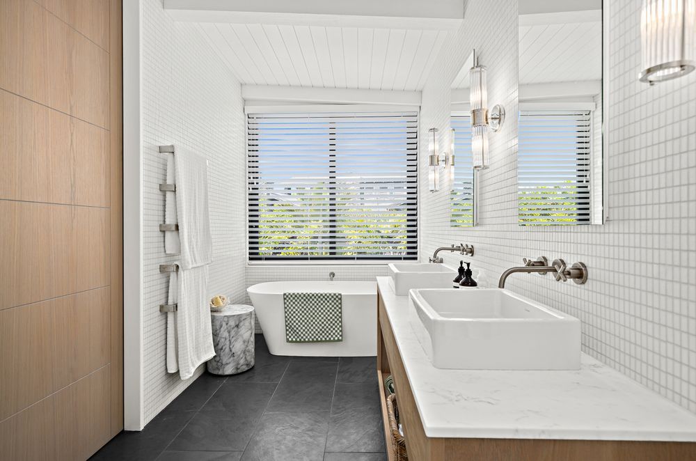 A Carrara marble benchtop pairs with white Vixel glass mosaic tiles from Artedomus in the main bathroom.