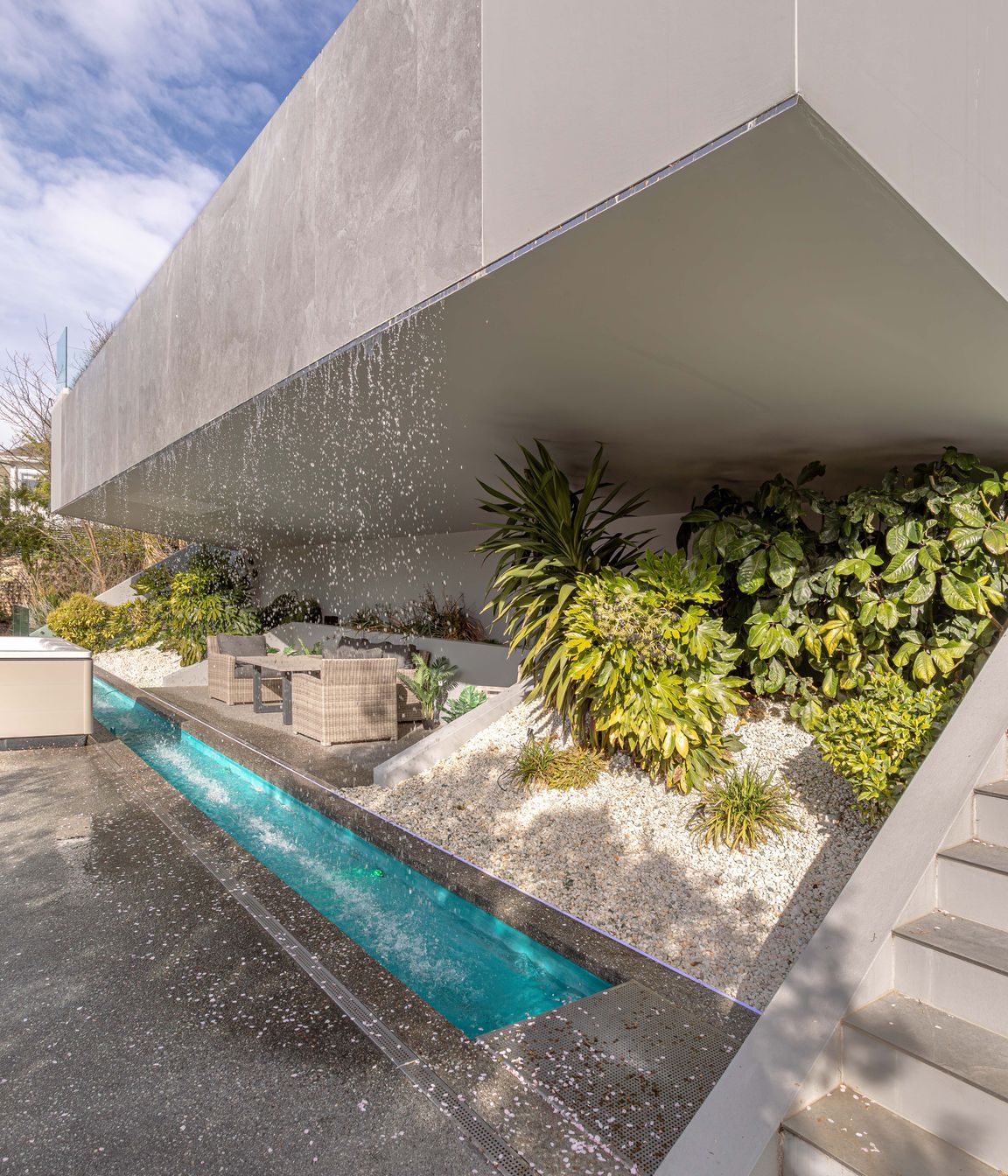 An intimate grotto is recessed behind the waterfall's downpour, complemented by lush foliage.