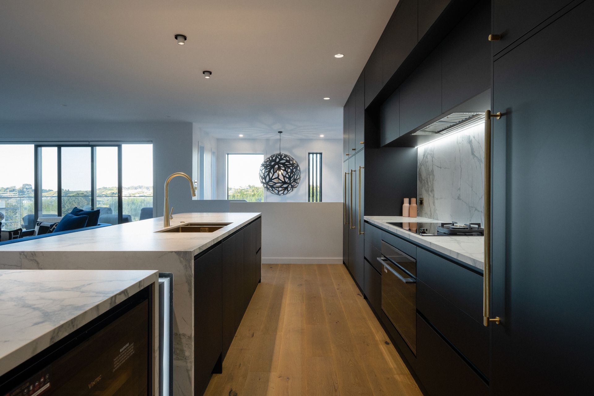 A contrast to the porcelain bench, the kitchen cabinetry is sleek in black – contrasting also with the brass handles.