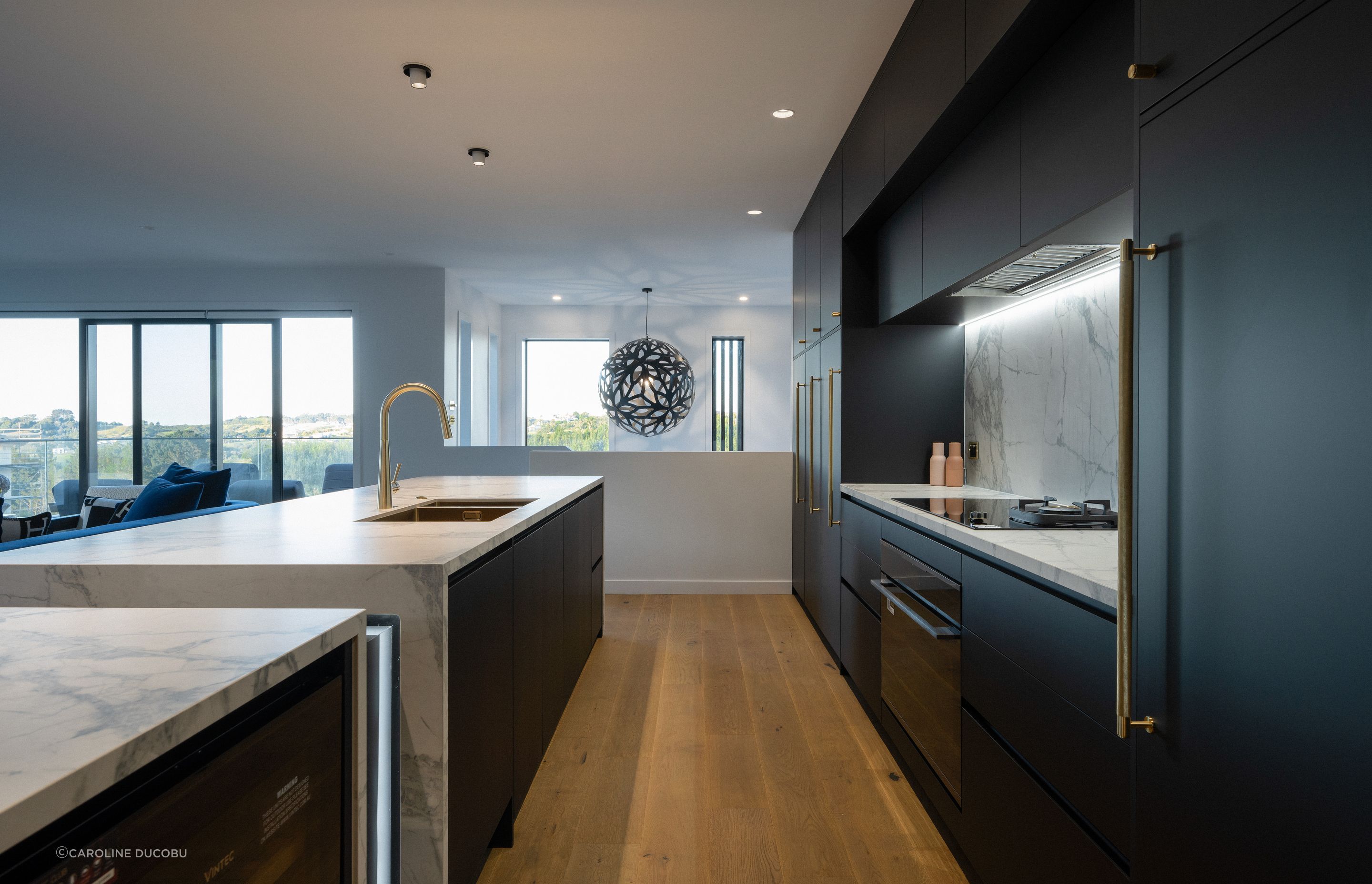 A contrast to the porcelain bench, the kitchen cabinetry is sleek in black – contrasting also with the brass handles. 