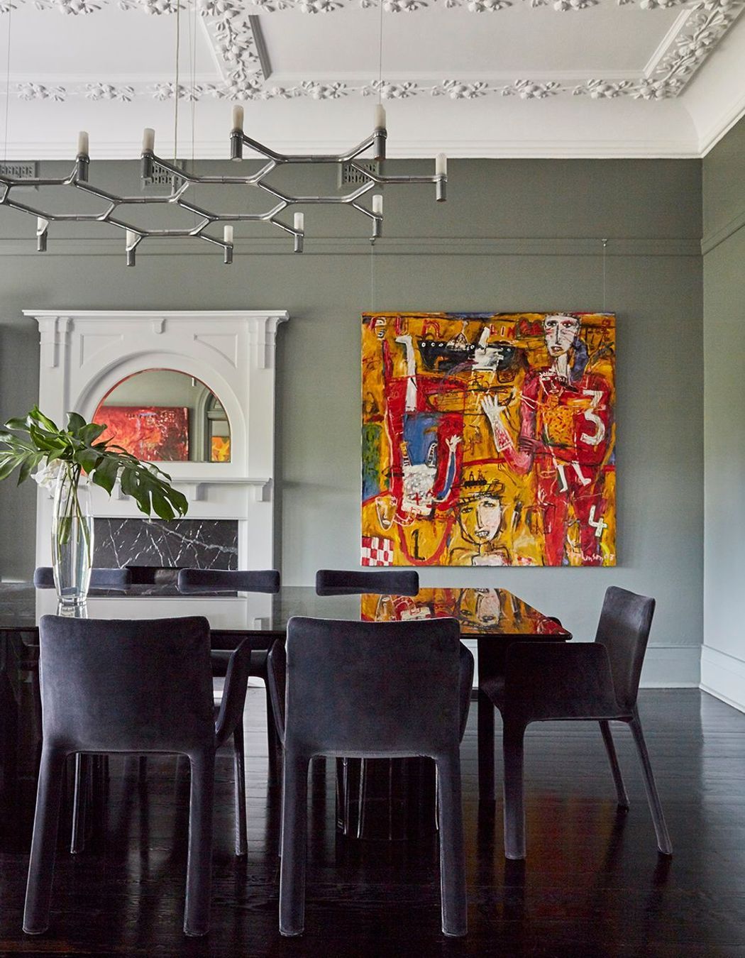 The dining room's dark inky table and chairs integrate with dark, glossy floors.
