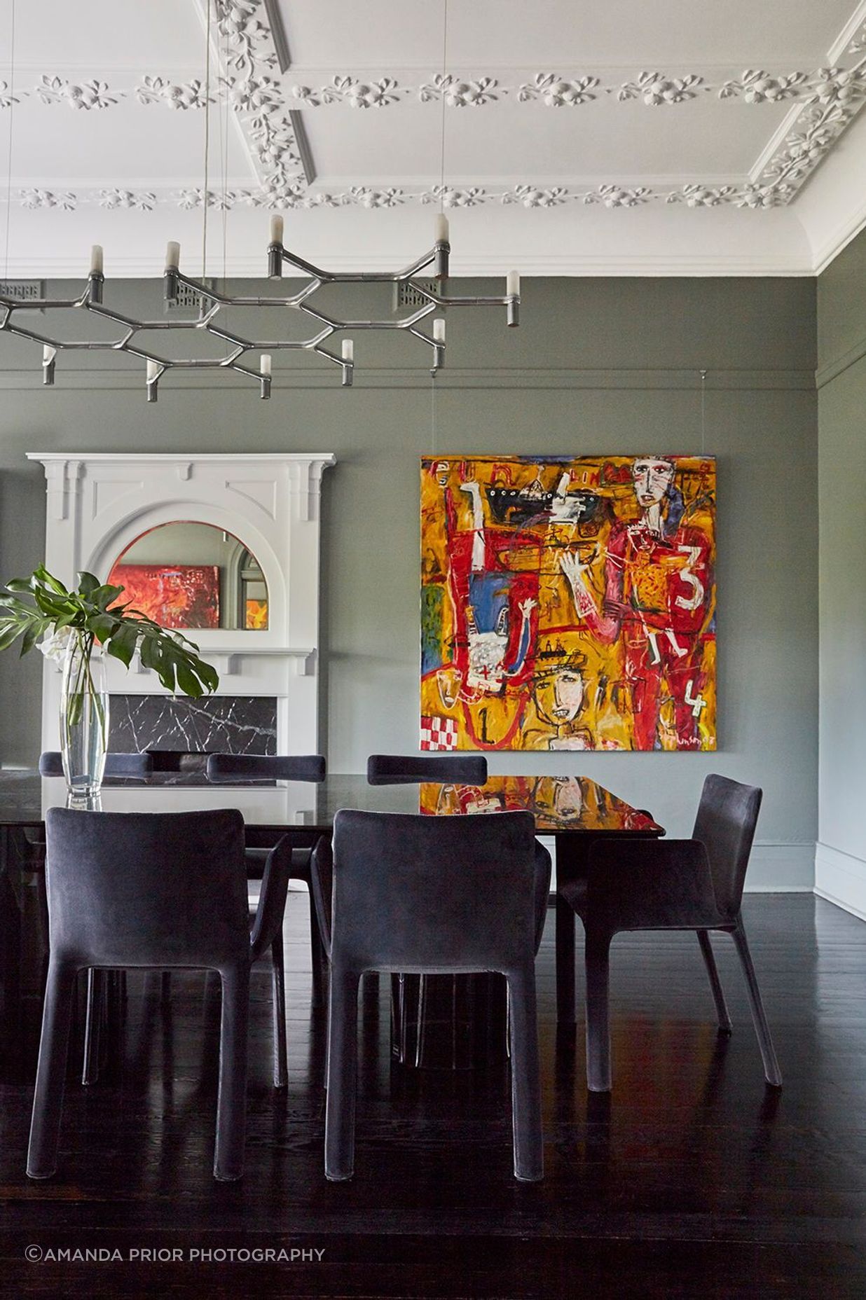 The dining room's dark inky table and chairs integrate with dark, glossy floors.