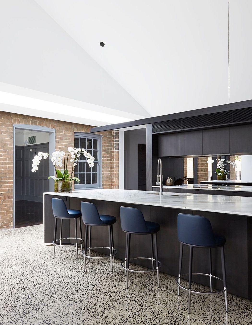 The kitchen features dramatic dark cabinetry that contrasts against the stone benchtop.
