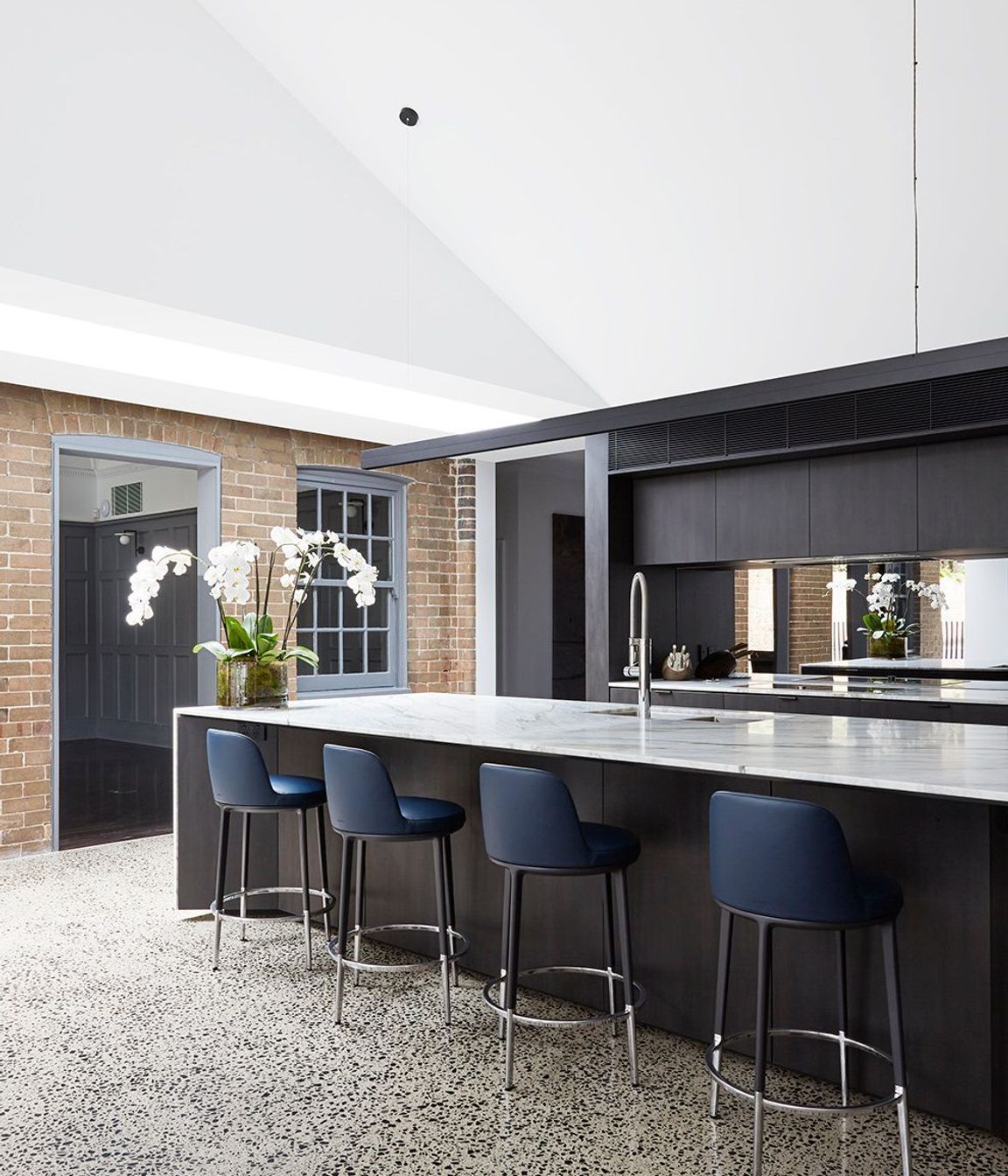 The kitchen features dramatic dark cabinetry that contrasts against the stone benchtop.