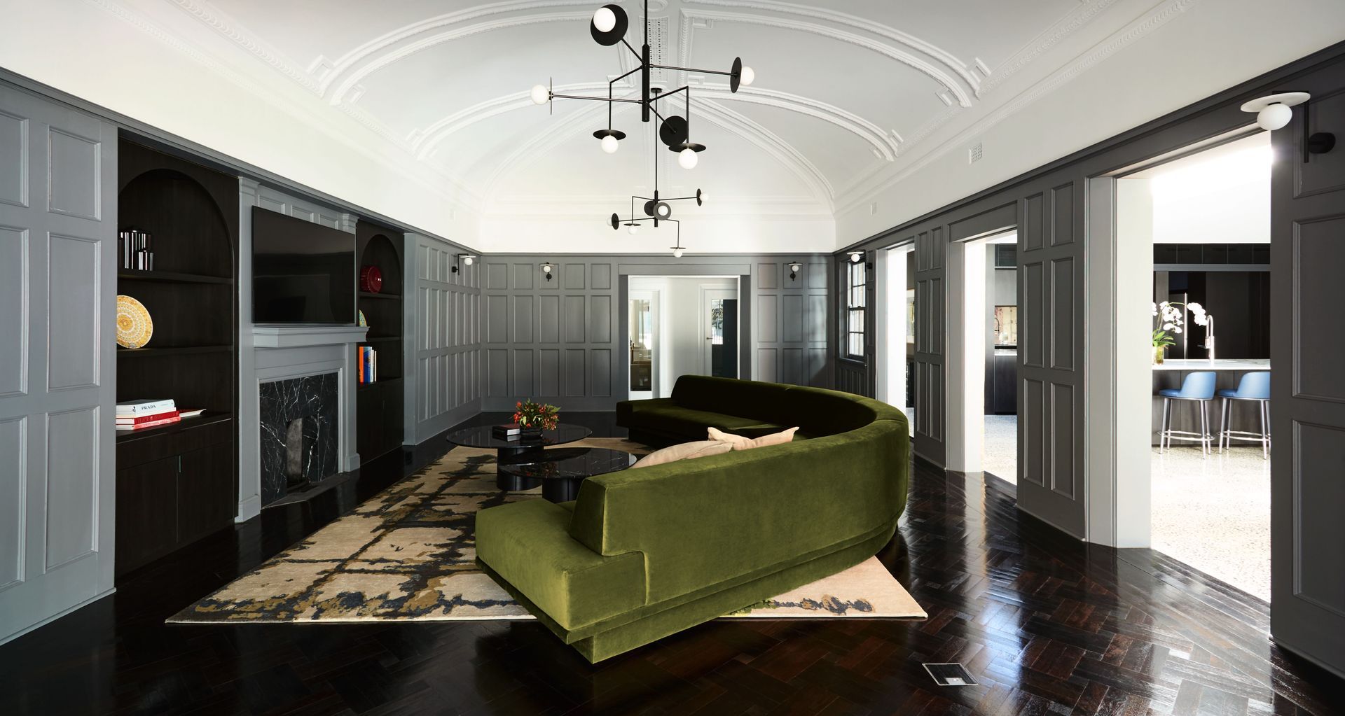 The ballroom, created for the weddings of the original owners' daughters is now a sumptuous family living room with a curved velvet couch that mimics the ceiling detail. Image credit: Amanda Prior Photography.