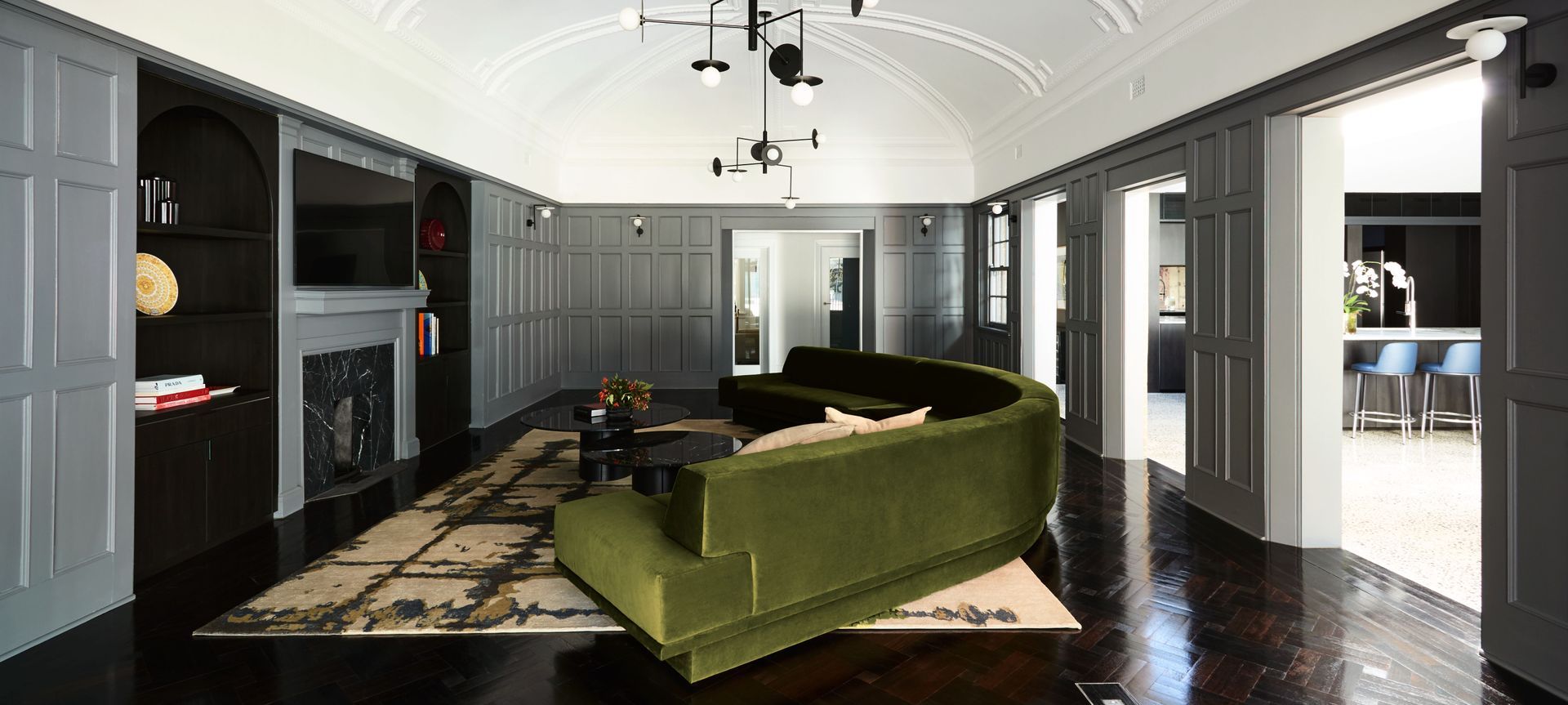 The ballroom, created for the weddings of the original owners' daughters is now a sumptuous family living room with a curved velvet couch that mimics the ceiling detail. Image credit: Amanda Prior Photography.