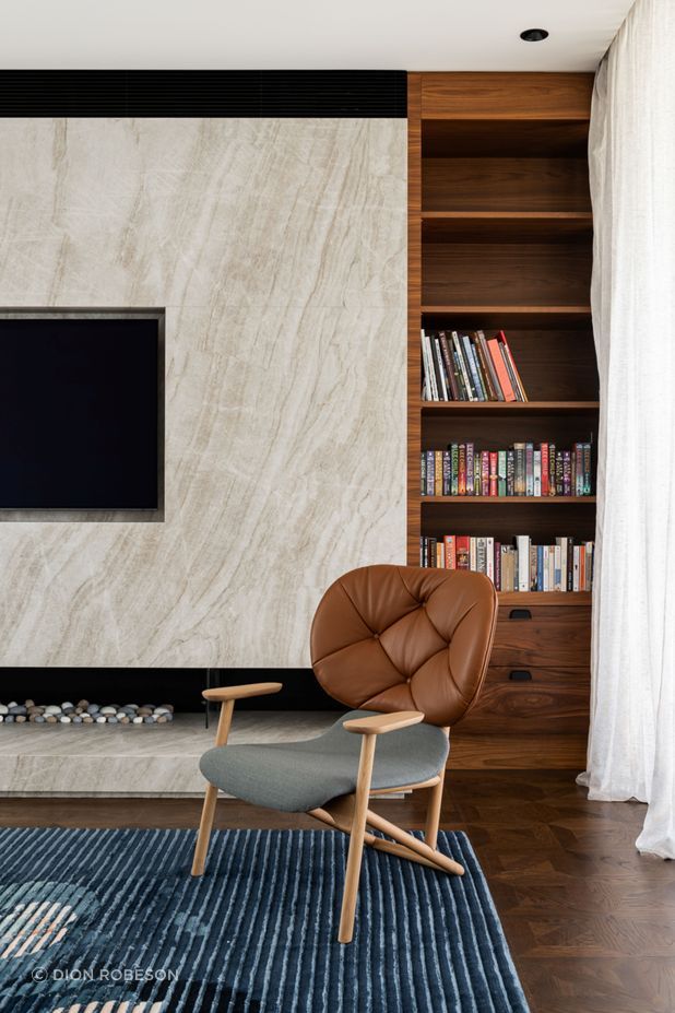Solid walnut shelves juxtapose against a sleek stone fireplace, giving the lounge space an opulent feel.