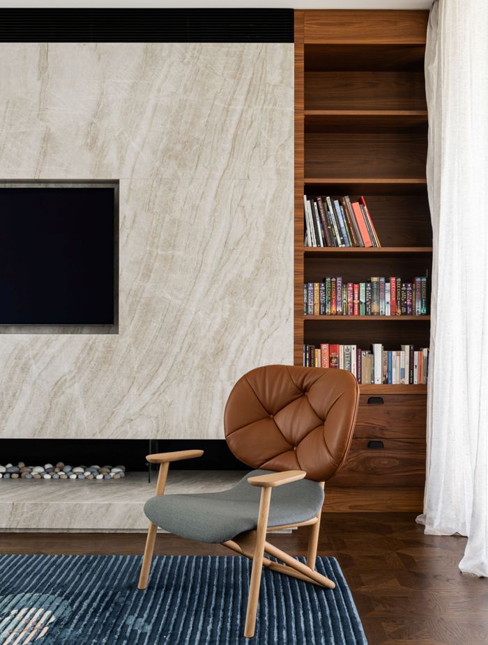 Solid walnut shelves juxtapose against a sleek stone fireplace, giving the lounge space an opulent feel.