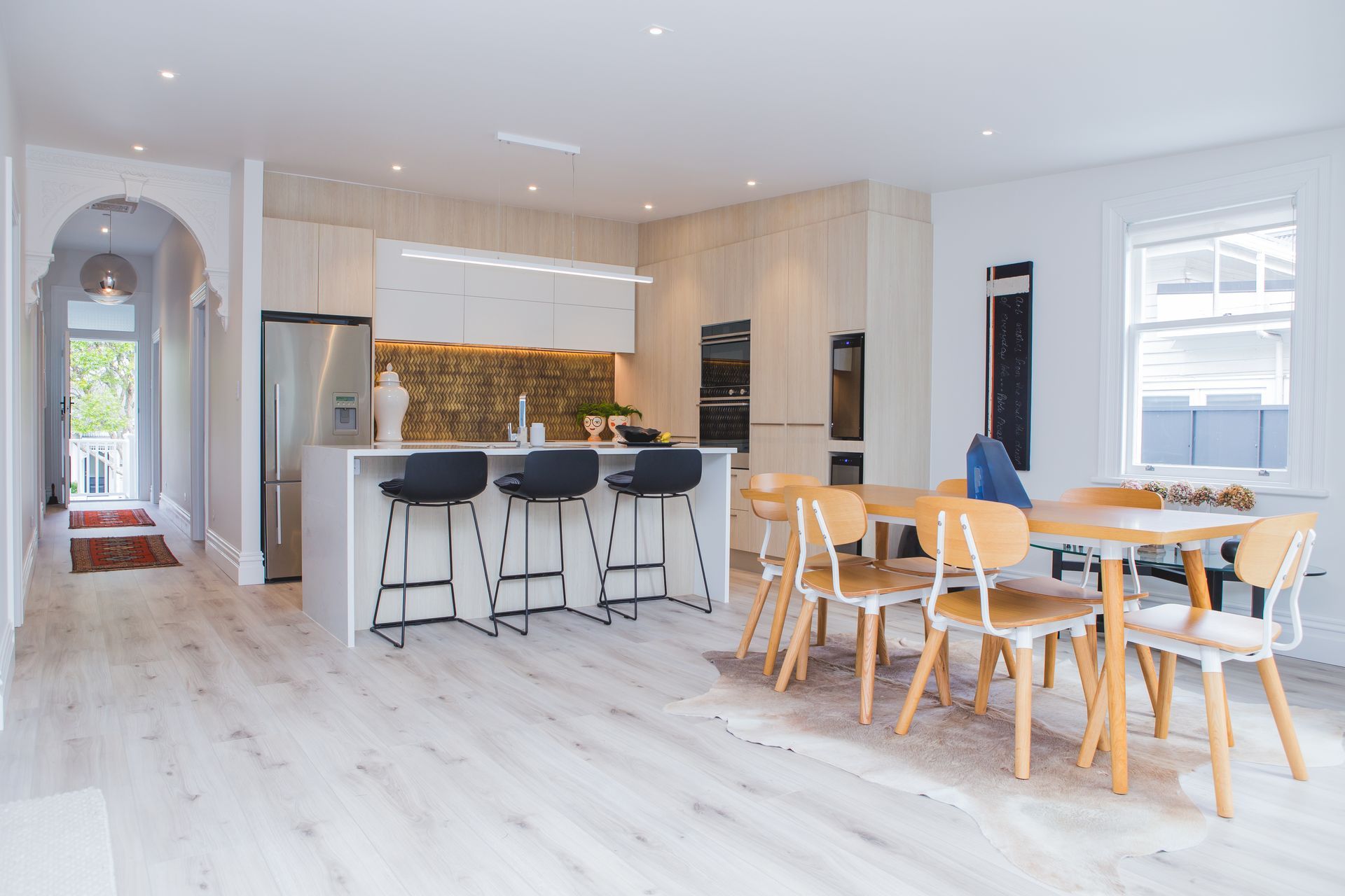 The open-plan kitchen and dining area is found beyond the hallway arch which defines the existing floorpan from the addition. The renovation also involved the installation of Autex Greenstuf to insulate the home.