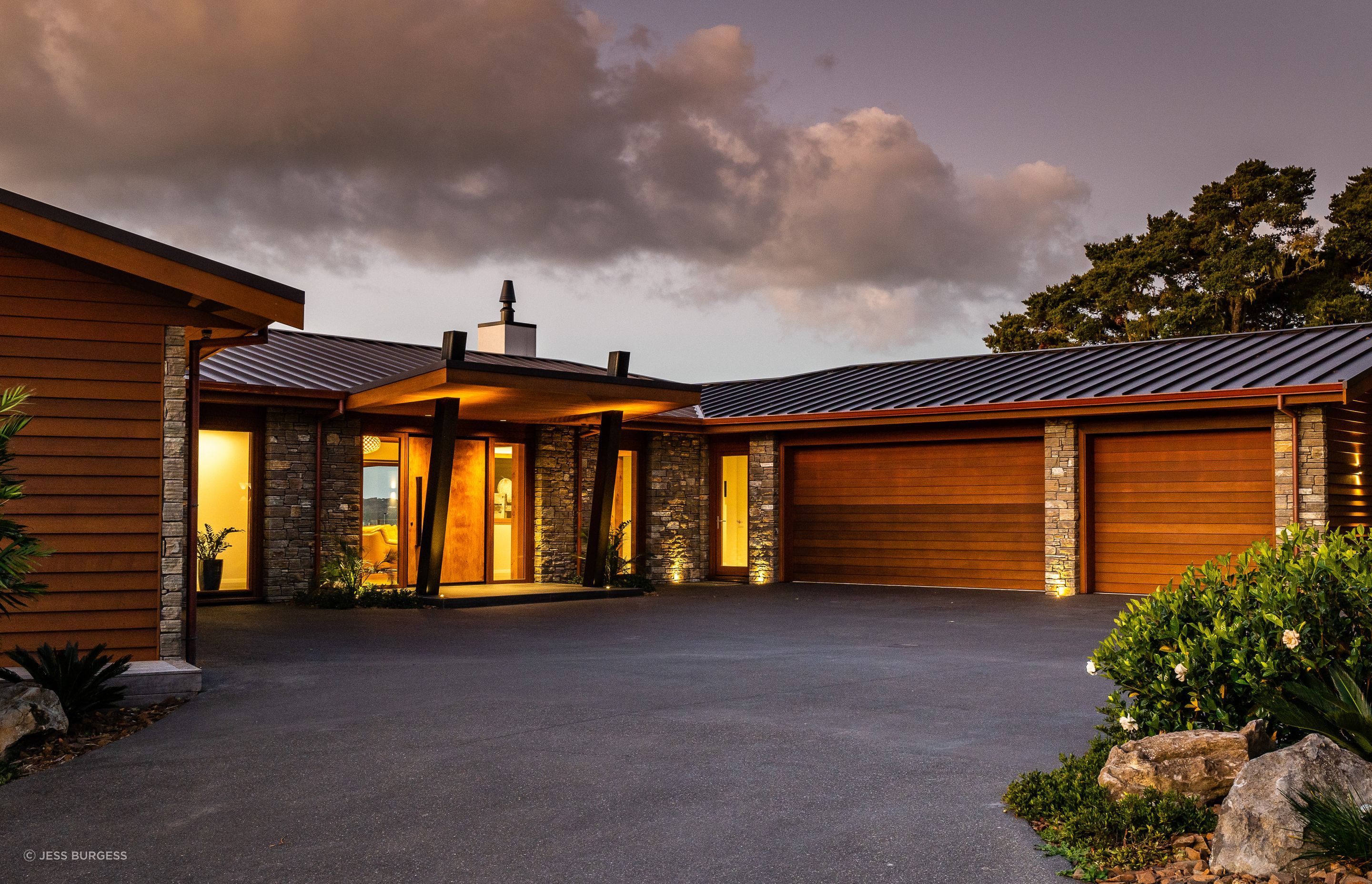 The house overlooking Paihia’s waterfront was built for a semi-retired couple. The pivot door is made from timber the homeowners had been saving. “We put a steel frame on it to stop it twisting because it’s so big,” says Alan Simpkin of Arcline Architecture. The homeowners requested a three-car garage, and the driveway required careful planning for vehicle movement as it exits to a narrow road on a hairpin bend.