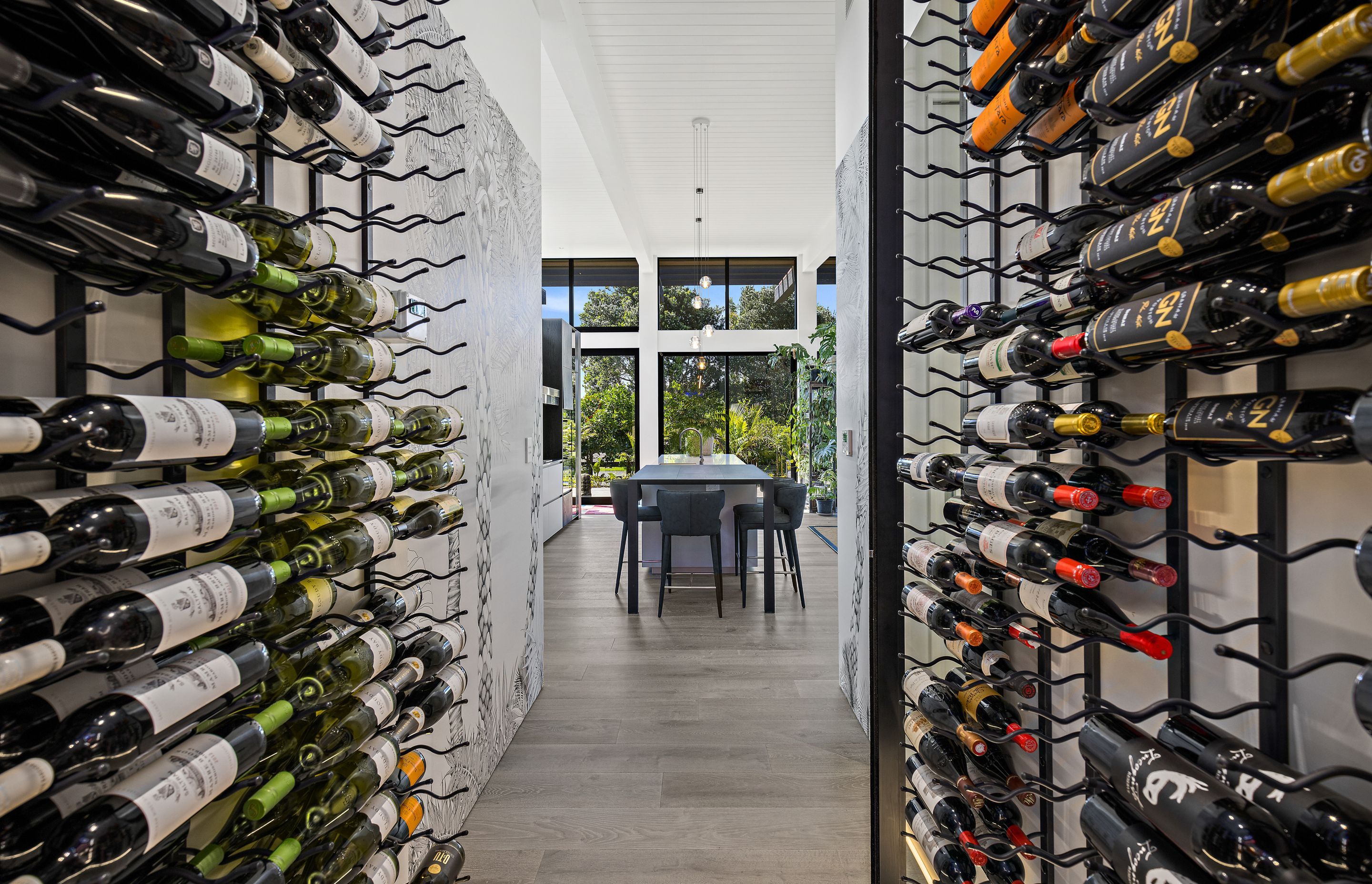The wine cellar is located close to the kitchen. A palm tree mural at the opening is a nod to the home’s coastal location.