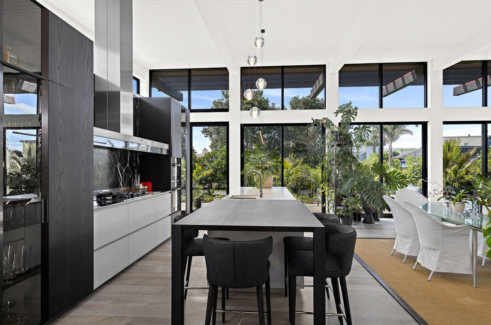Dark wood veneer kitchen cabinetry supplied and installed by Studio Italia complements the home’s exterior – contrasting with the Pumice French oak flooring from Artedomus. A Bocci 5 pendant from ECC lighting is suspended above the island bench.