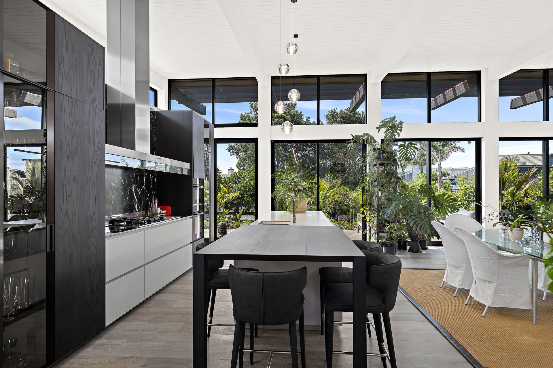Dark wood veneer kitchen cabinetry supplied and installed by Studio Italia complements the home’s exterior – contrasting with the Pumice French oak flooring from Artedomus. A Bocci 5 pendant from ECC lighting is suspended above the island bench.