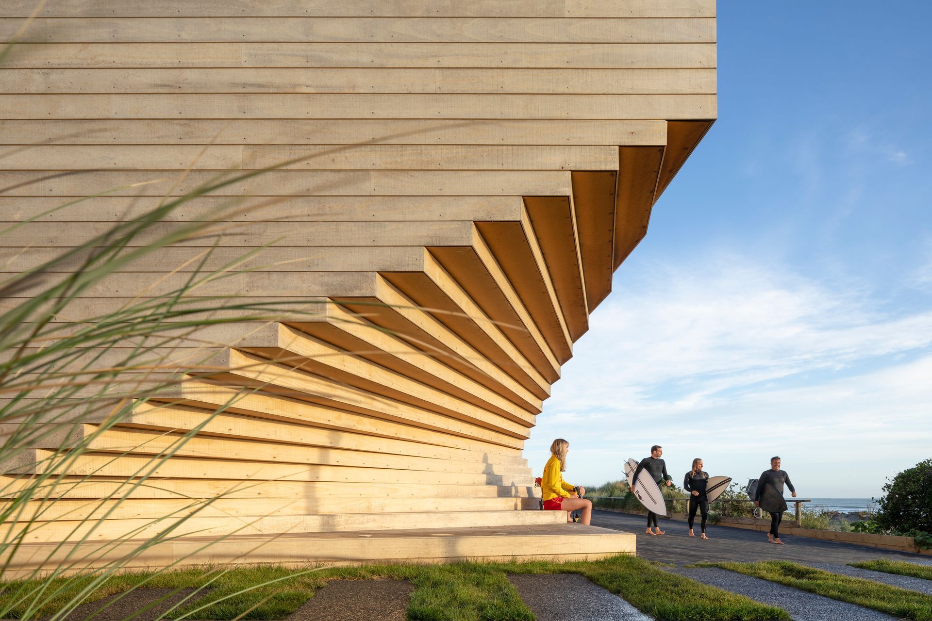 Fanning towards the ocean, the building's architectural form mimics the curves and undulations in the surrounding sand and driftwood.