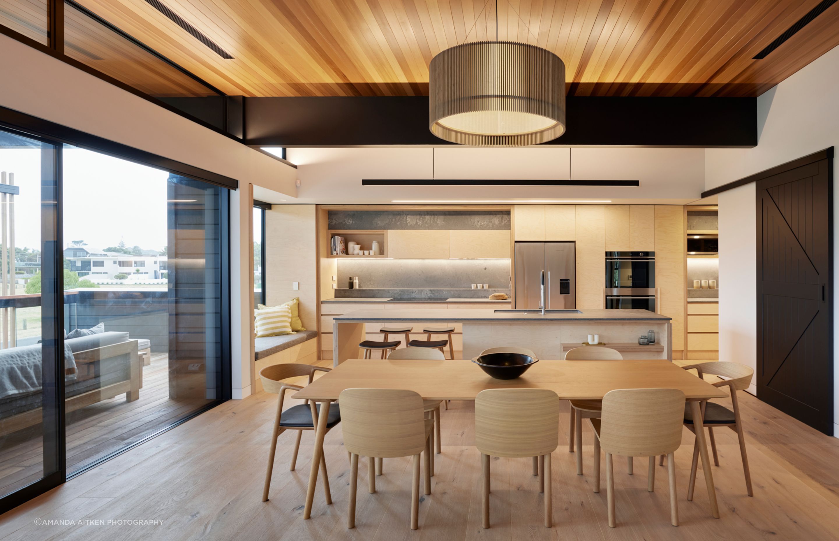 The plywood kitchen finishes and the barn-door style were chosen to keep to a relaxed beachside feel.