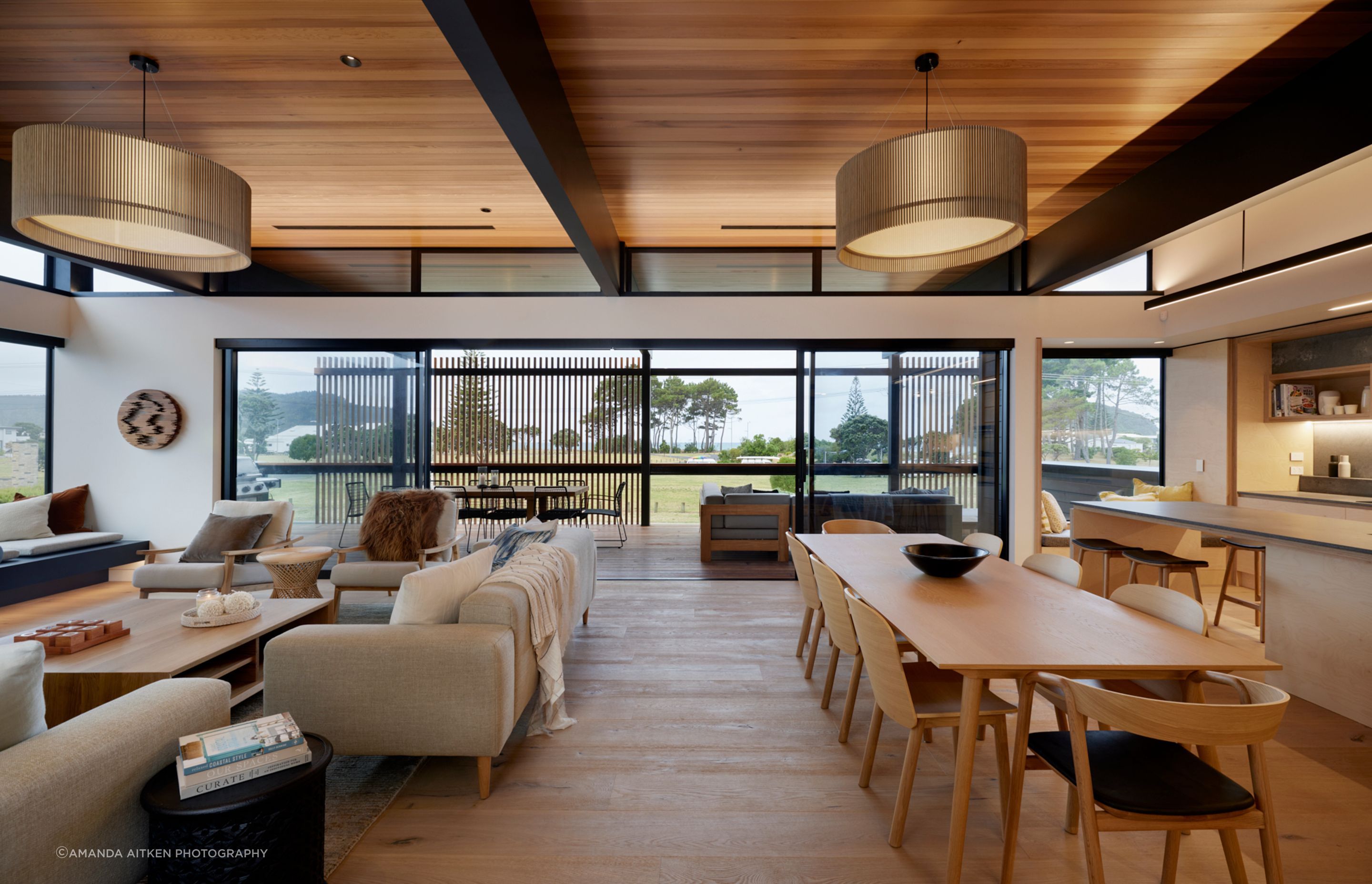 The front deck is carefully screened for a combination of views and privacy. The ceilings are lined in cedar. “We integrate a lot of the lighting,” says Brendon. “We have a lot of bespoke LED lighting which is nice and discreet. Lighting can set different scenes and change the whole feel of a room.” The pendants are iO lights by Maker Design Studio in Tauranga.