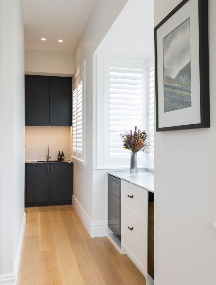 The scullery tucked around a corner hides a second refrigerator. The dark cabinetry in Resene Double Tuna echoes the dark marble used in the kitchen.