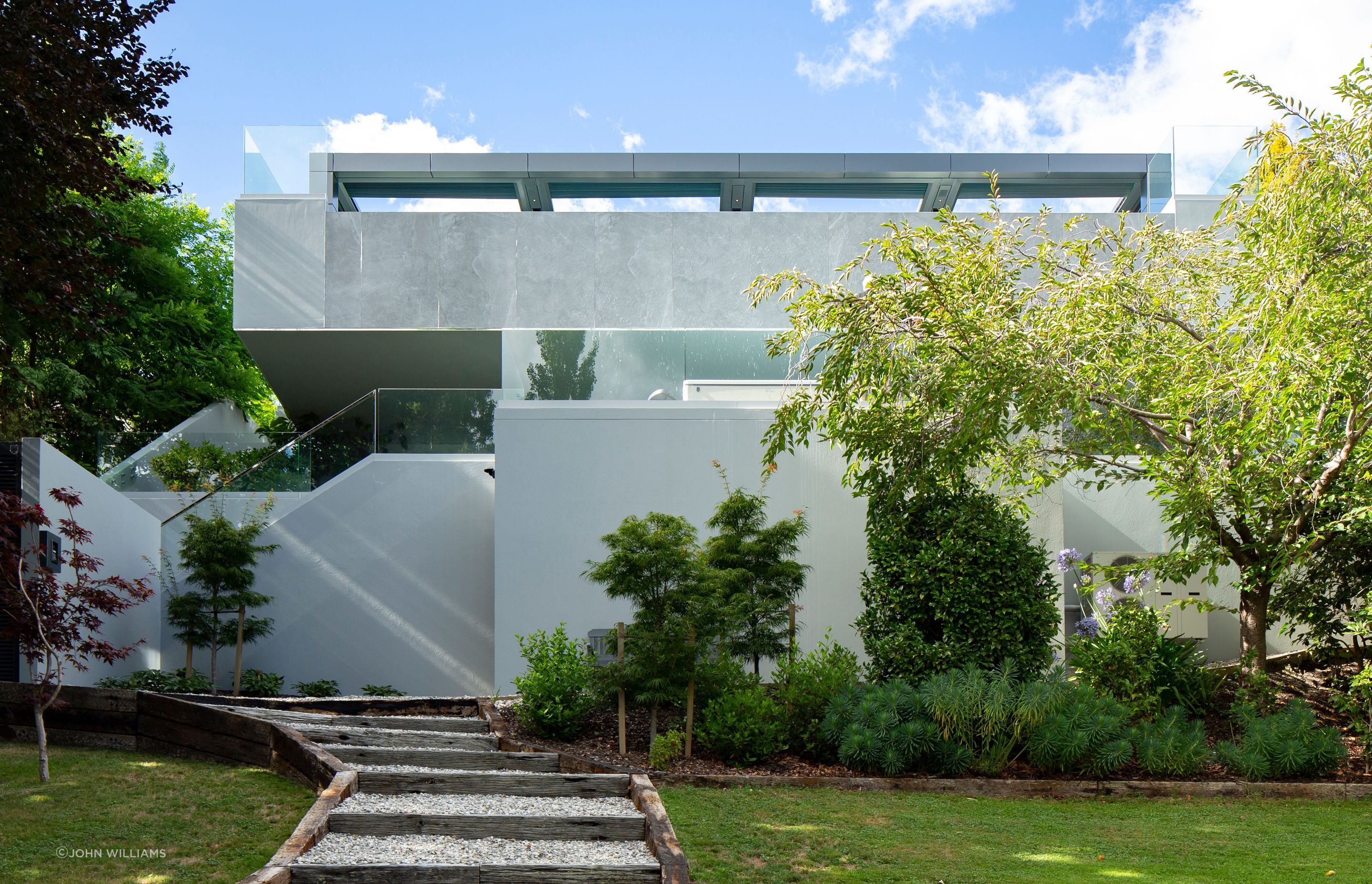 The lowest level is met by the deep greens of an established, landscaped garden and the rich blues of Lake Wakatipu.