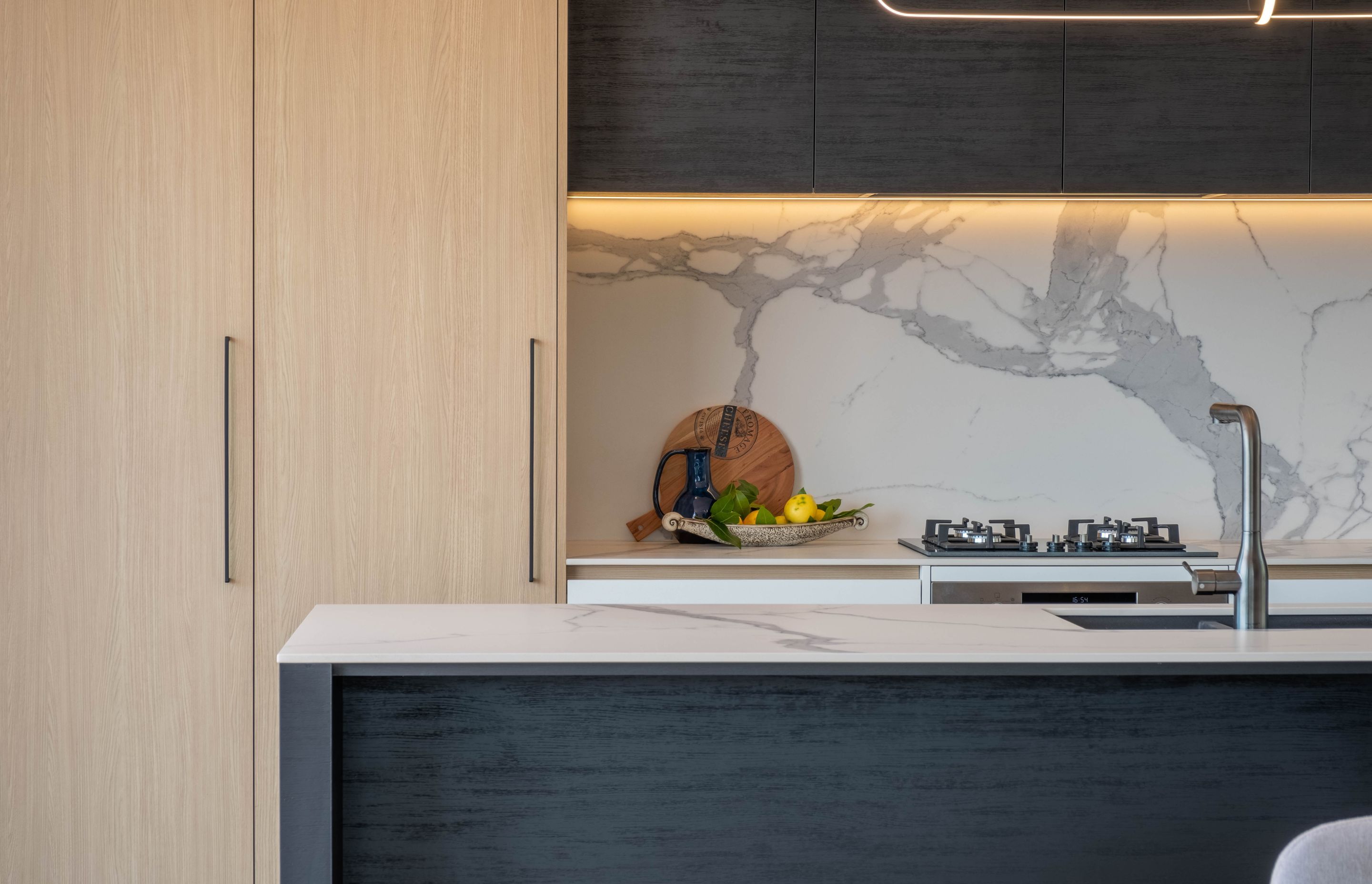 Aged ash and black kitchen cabinetry with integrated appliances complement the rest of the home’s neutral colour palette.