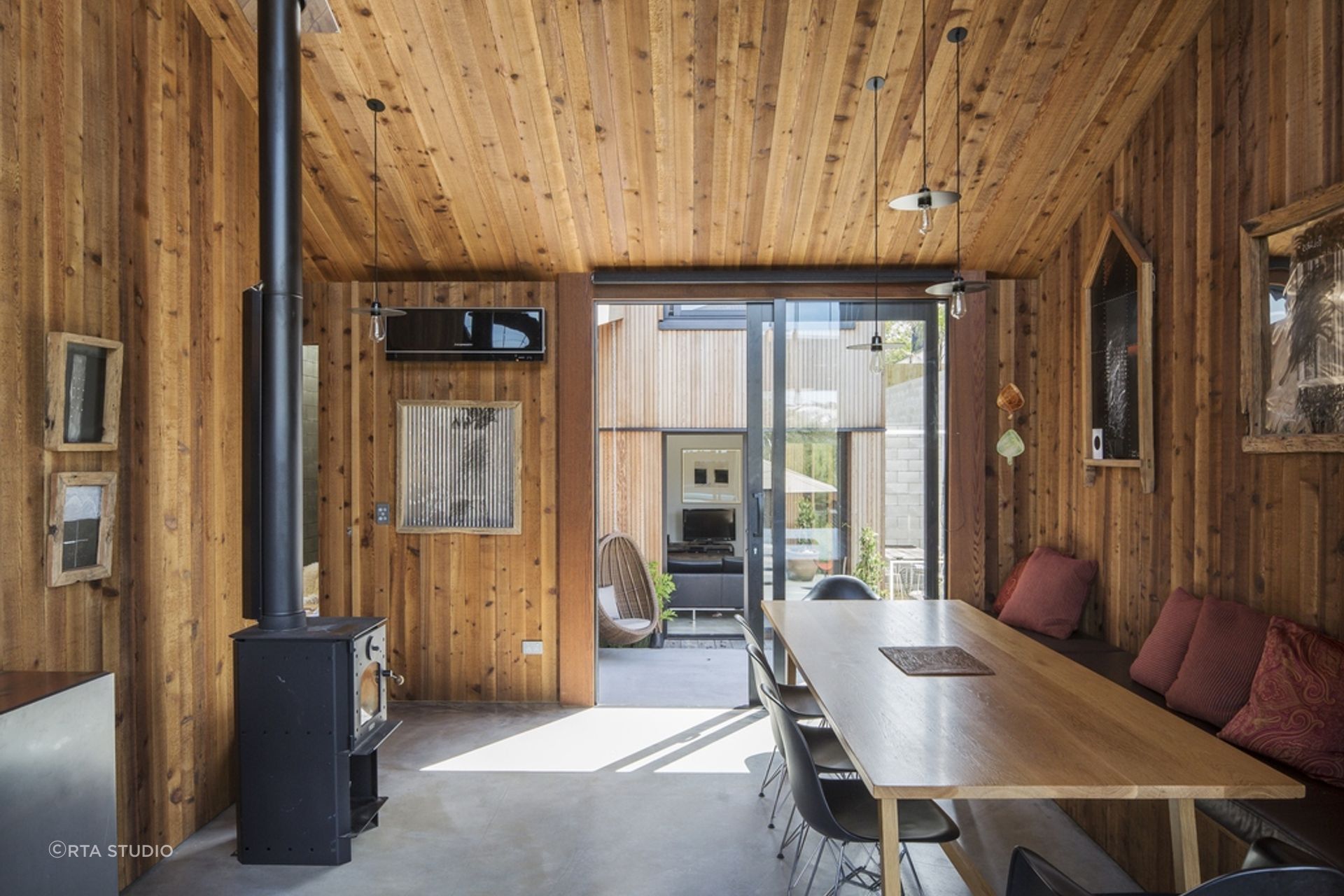 The timber panelling creates a seamless transition between the indoor and outdoor spaces, with cedar weatherboards cladding the exterior.