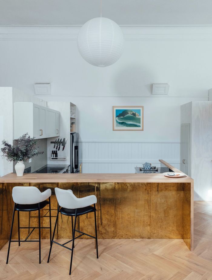 The kitchen features a timber breakfast bar and brass details. 