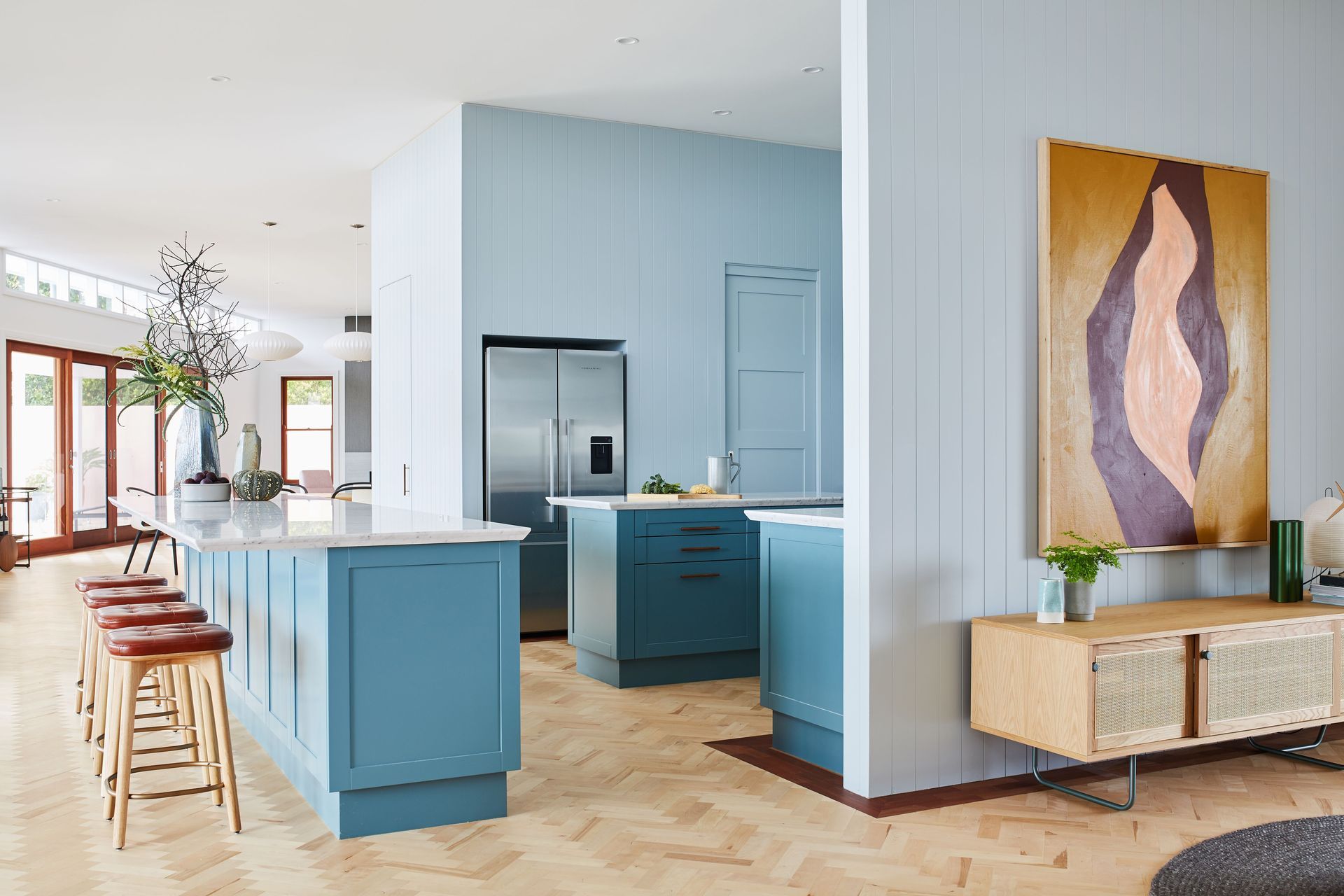 The soft dusty blue wraps around both sides of the kitchen walls and contrasts serenely with the teal cabinetry.