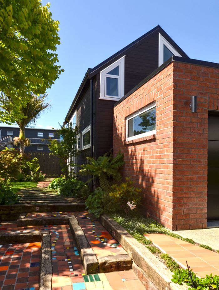 The tiny home is tucked behind a brick-clad garage.