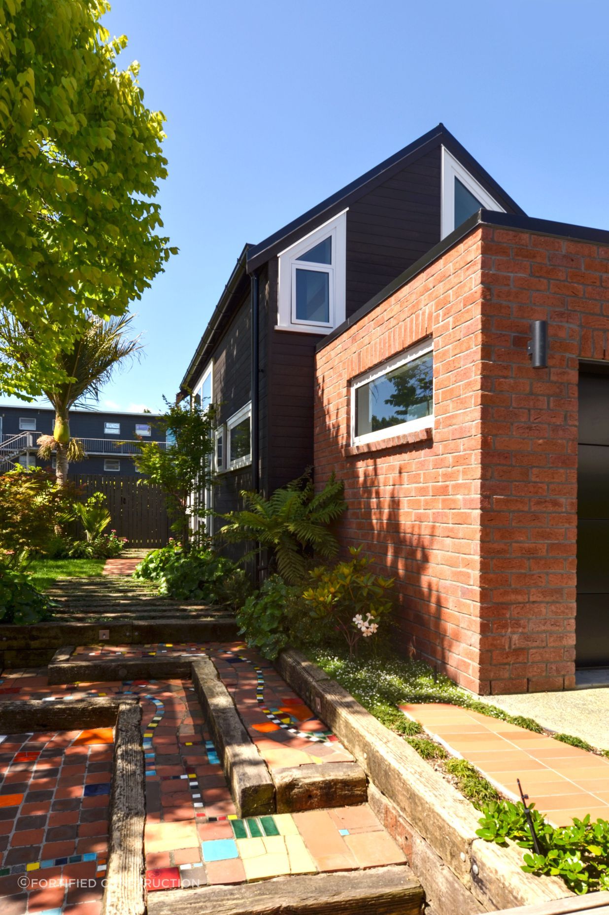 The tiny home is tucked behind a brick-clad garage.