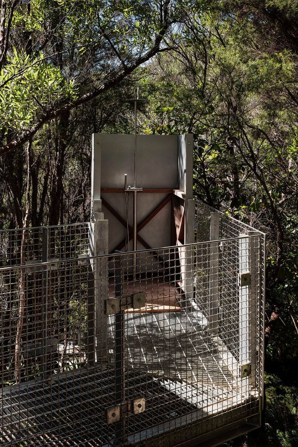 A grated metal walkway meets a shower deep in the forest.