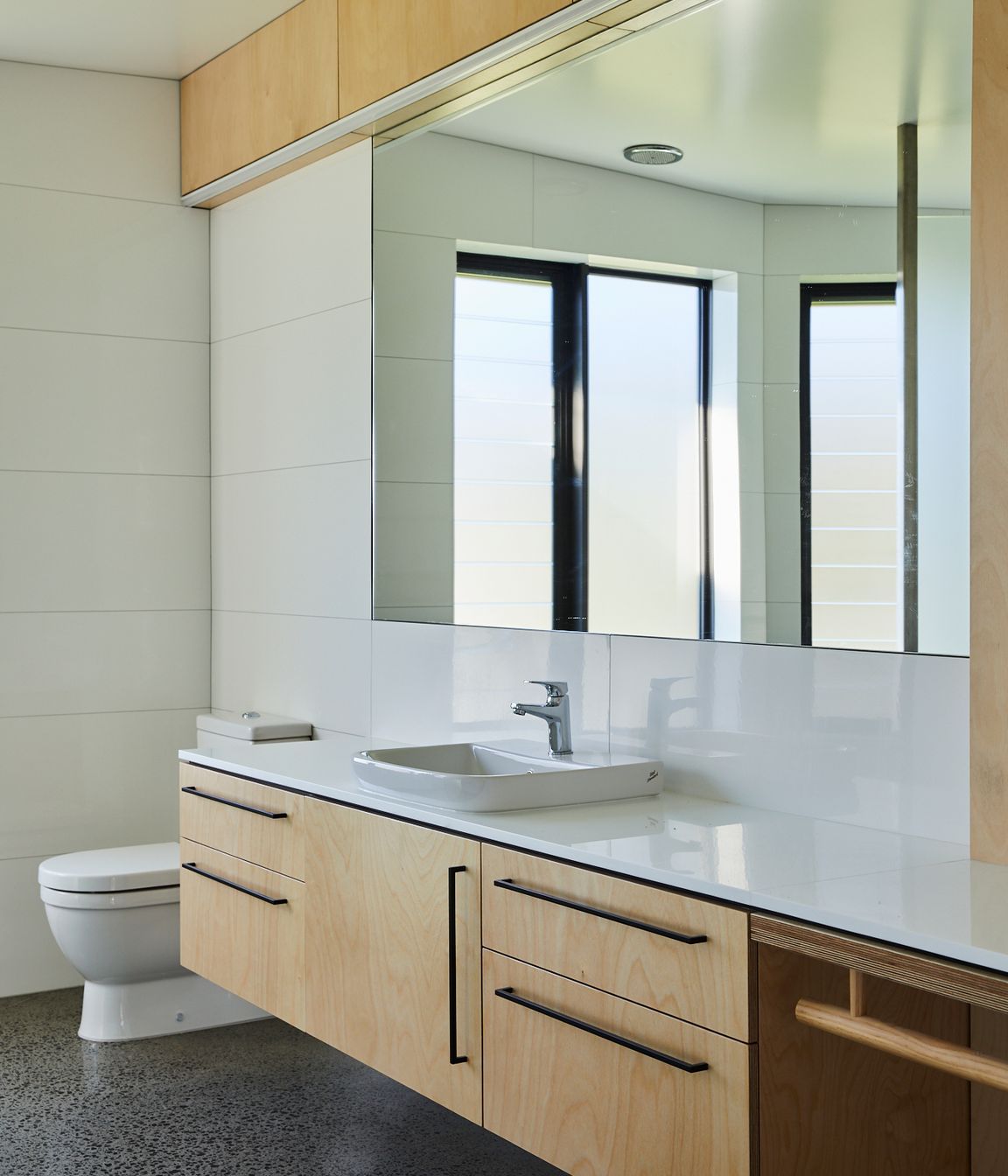 The white Marazzi Essenziale Lux tiles are from The Tile People. Birch ply cabinetry carries through from the rest of the house and the black U Handles are by Katalog.