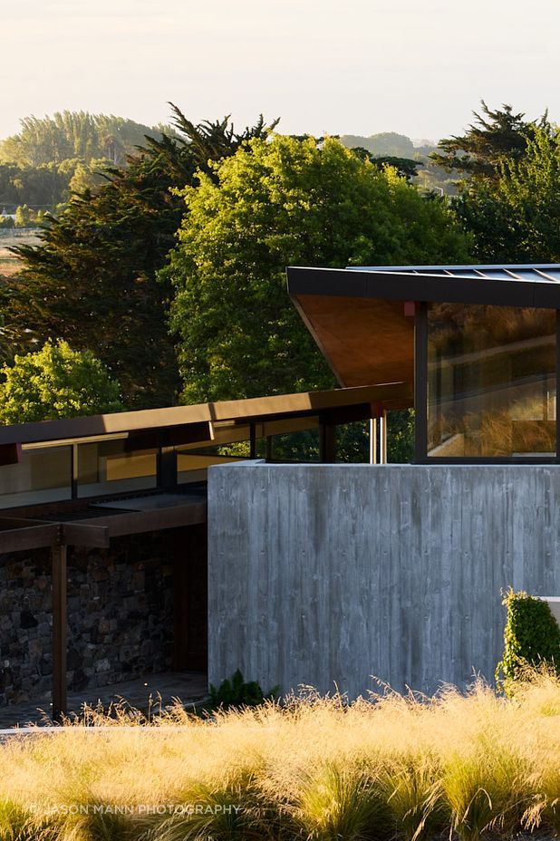 The home is embedded into the gently sloping site, anchored by heavy materials.