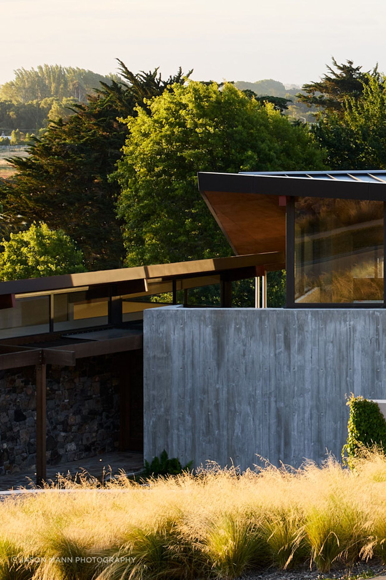 The home is embedded into the gently sloping site, anchored by heavy materials.