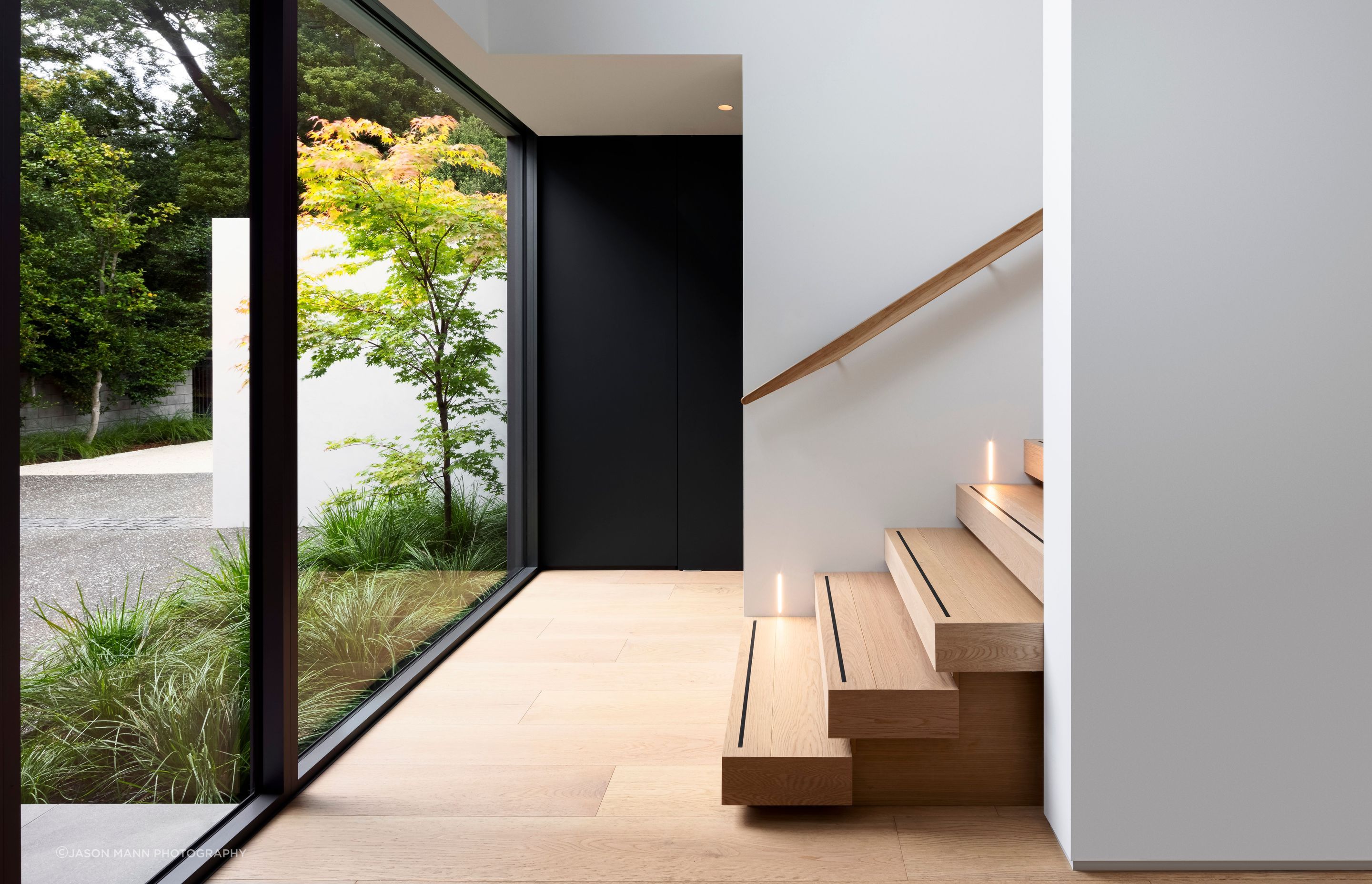Inside, the dramatic, double-height entry space is bright and welcoming, warmed by a timber staircase that leads upwards towards the second level.