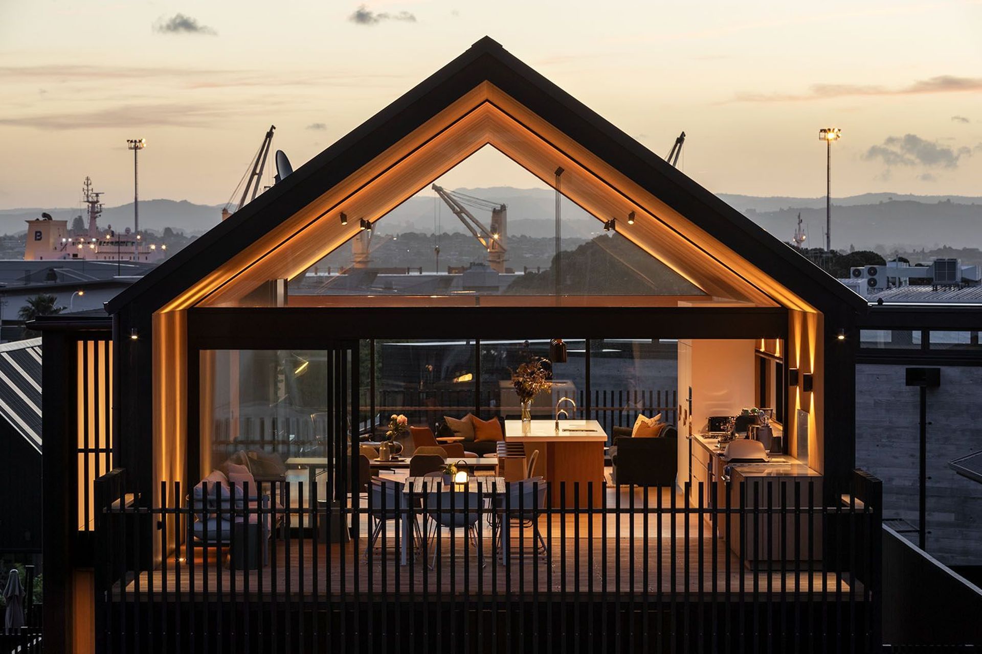 From the exterior, the building’s form celebrates the traditional gable roof, flanked by large swathes of triangular glass which enable elevated views of the harbour to the west and Mount Maunganui to the east.