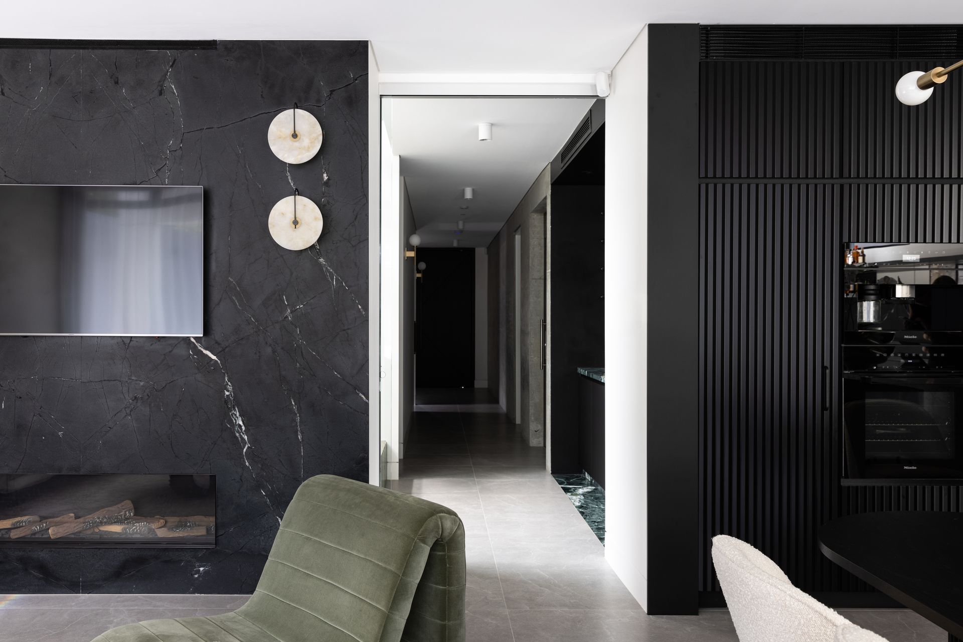 The moody interior scheme is really experienced in the kitchen, dining and living area with its black cabinetry and marble.