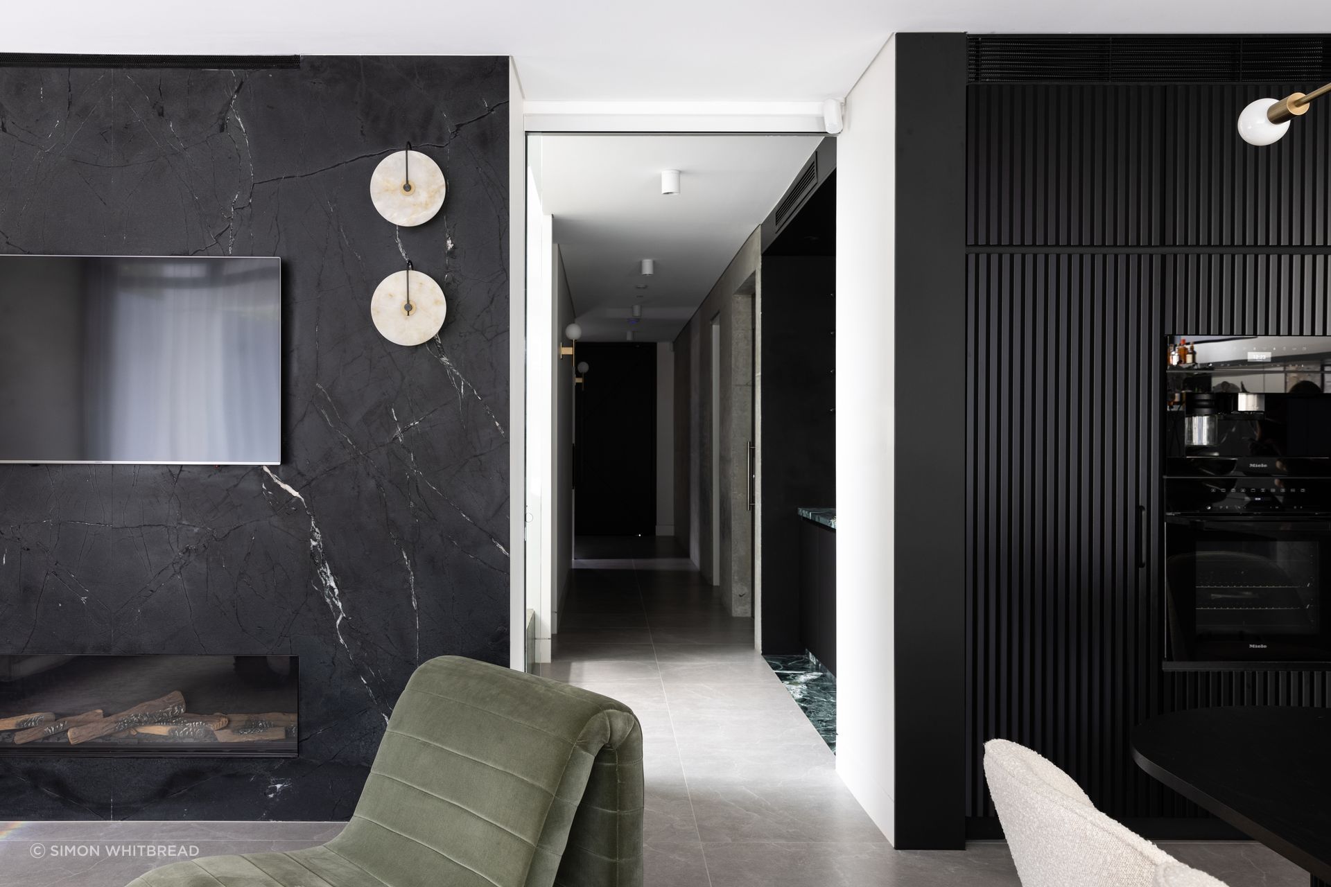 The moody interior scheme is really experienced in the kitchen, dining and living area with its black cabinetry and marble.