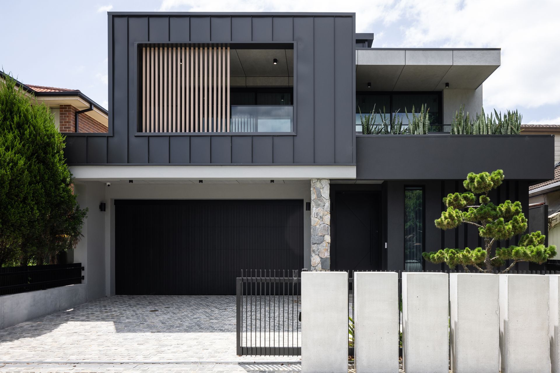 The exterior is a prelude to the interior: concrete, natural stones and dark surfaces.