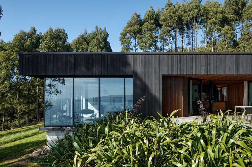 Black stained cedar cladding lines the exterior, laid with varying profiles relative to its location on the building.