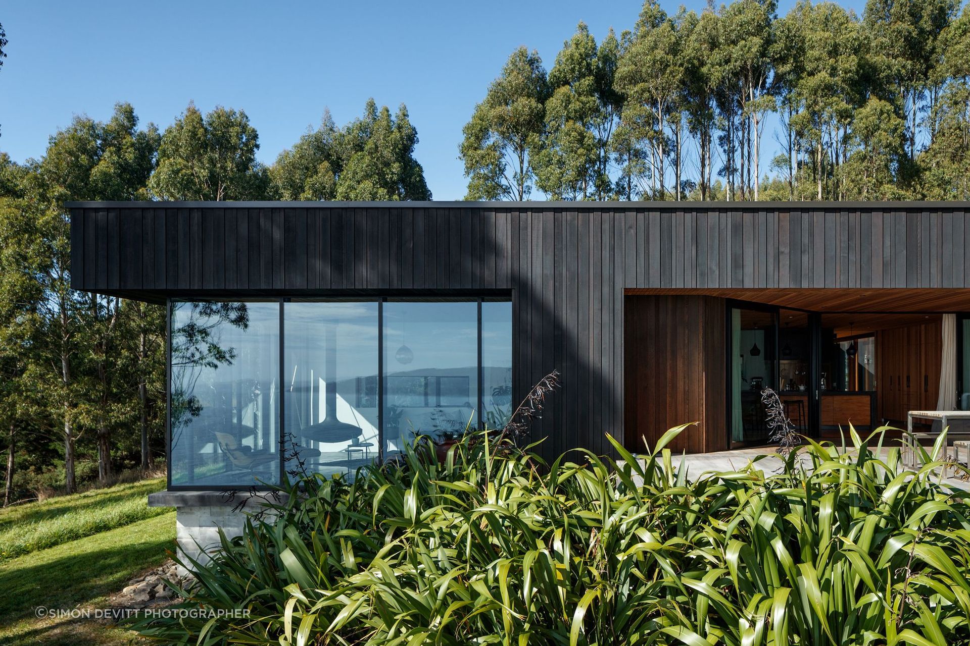 Black stained cedar cladding lines the exterior, laid with varying profiles relative to its location on the building.