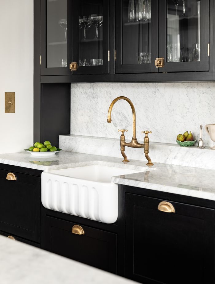 Brass hardware beautifully accents the black kitchen cabinetry.