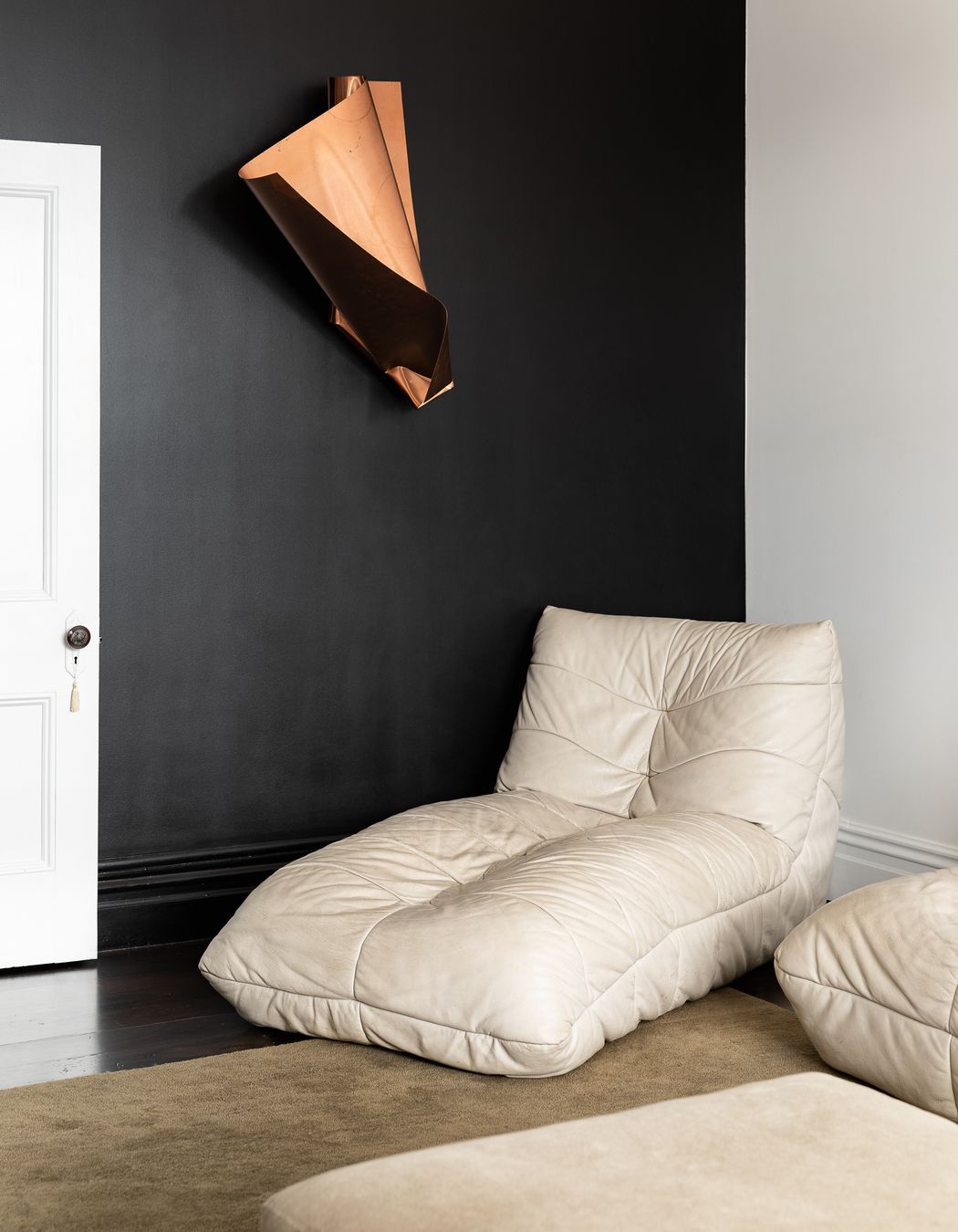 The black wall has been refinished and serves as the perfect canvas for the family's growing art collection. The chair is Babelogue and the rug is from Simon James.
