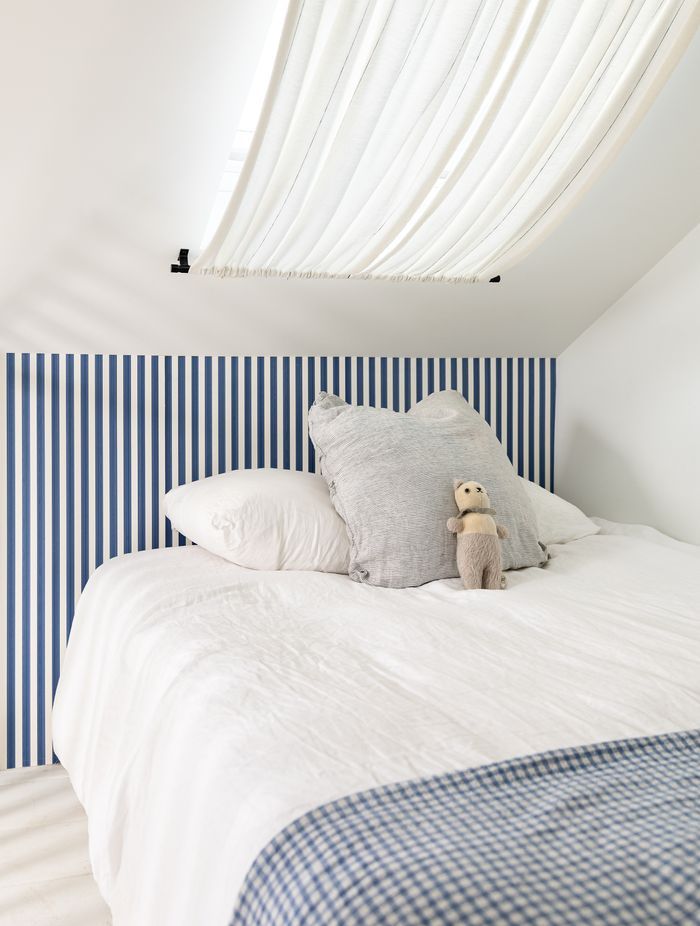 The blue-striped Farrow & Ball wallpaper brings a fun sailor's theme to the bedroom.
