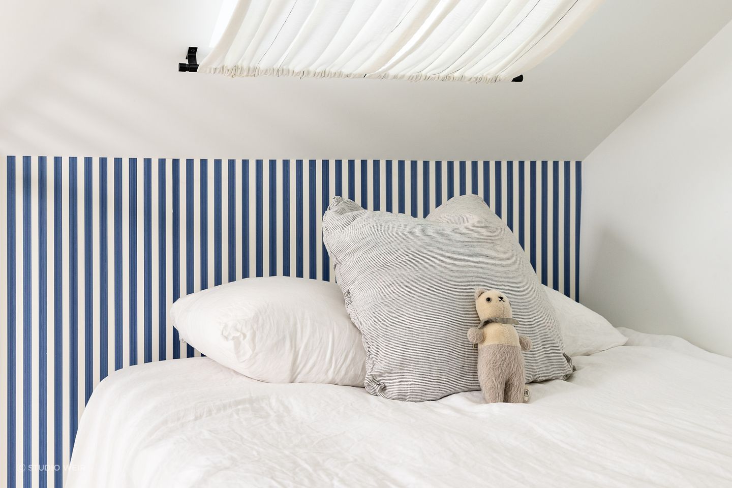The blue-striped Farrow & Ball wallpaper brings a fun sailor's theme to the bedroom.