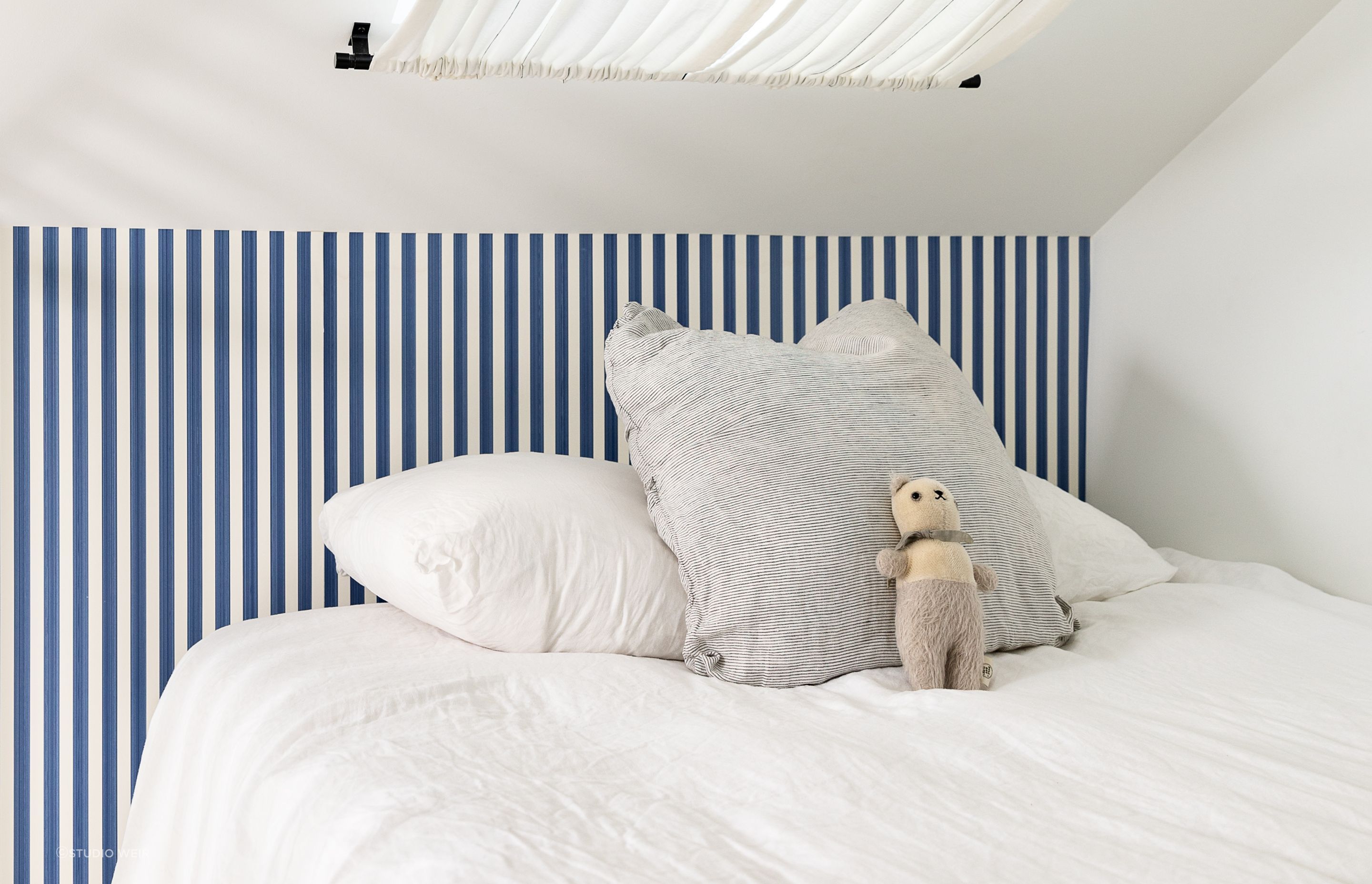 The blue-striped Farrow & Ball wallpaper brings a fun sailor's theme to the bedroom.