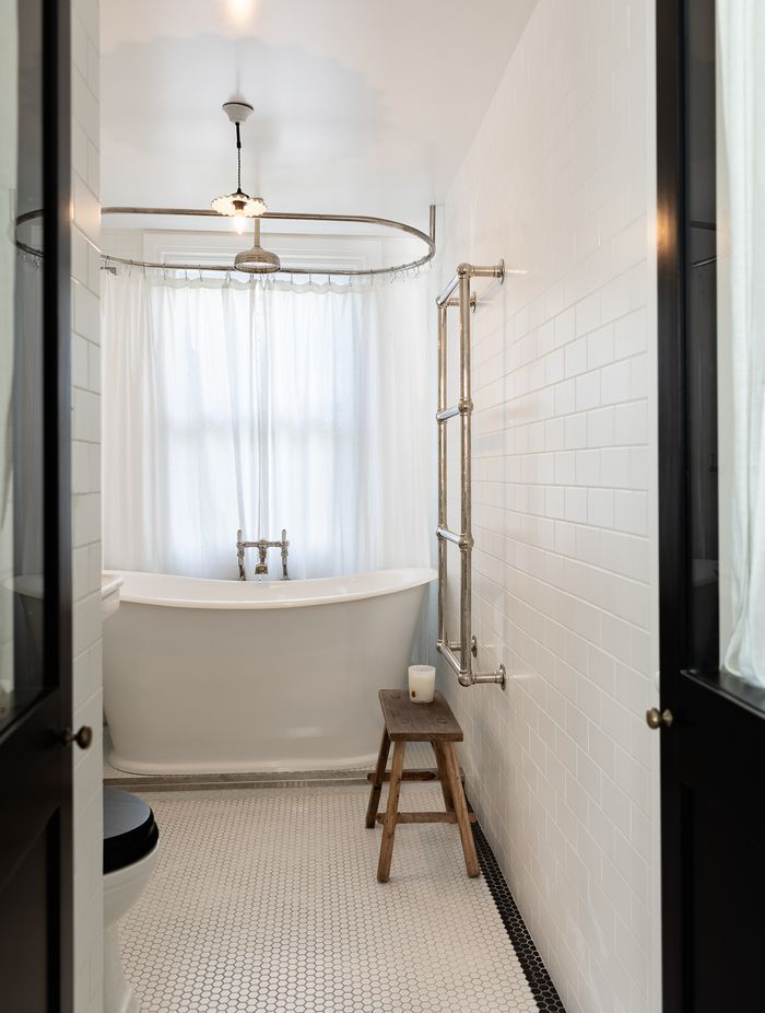 The children's bathroom features traditional butcher wall tiles and a bath from In Residence. The shower curtain ring is bespoke by Buxeda Construction.