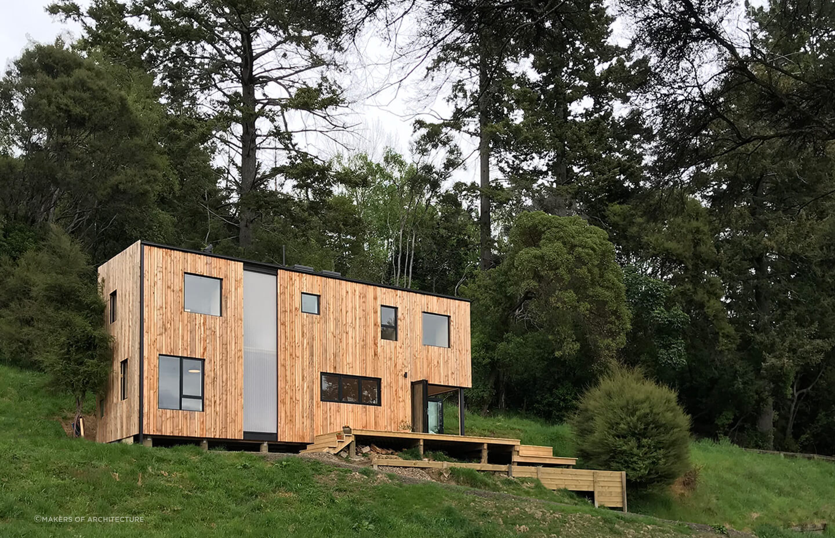 The dramatic exterior of the Akaroa Bach by Makers of Architecture in amongst manuka bush and rural farmland